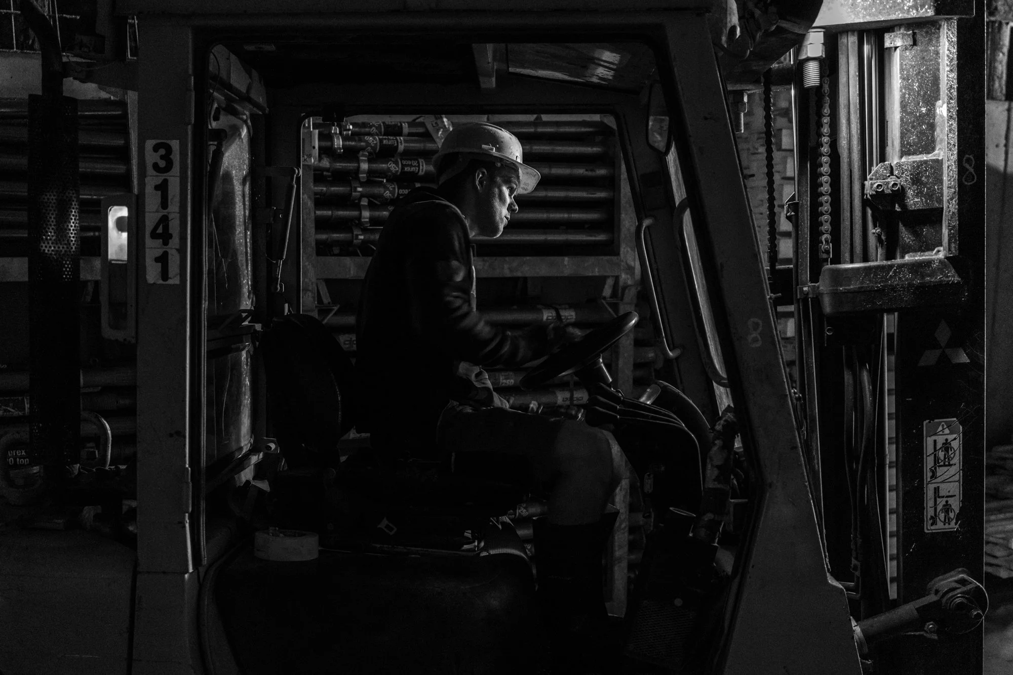 Een man die een vorkheftruck bedient in een werkplaats, zwart-wit foto.