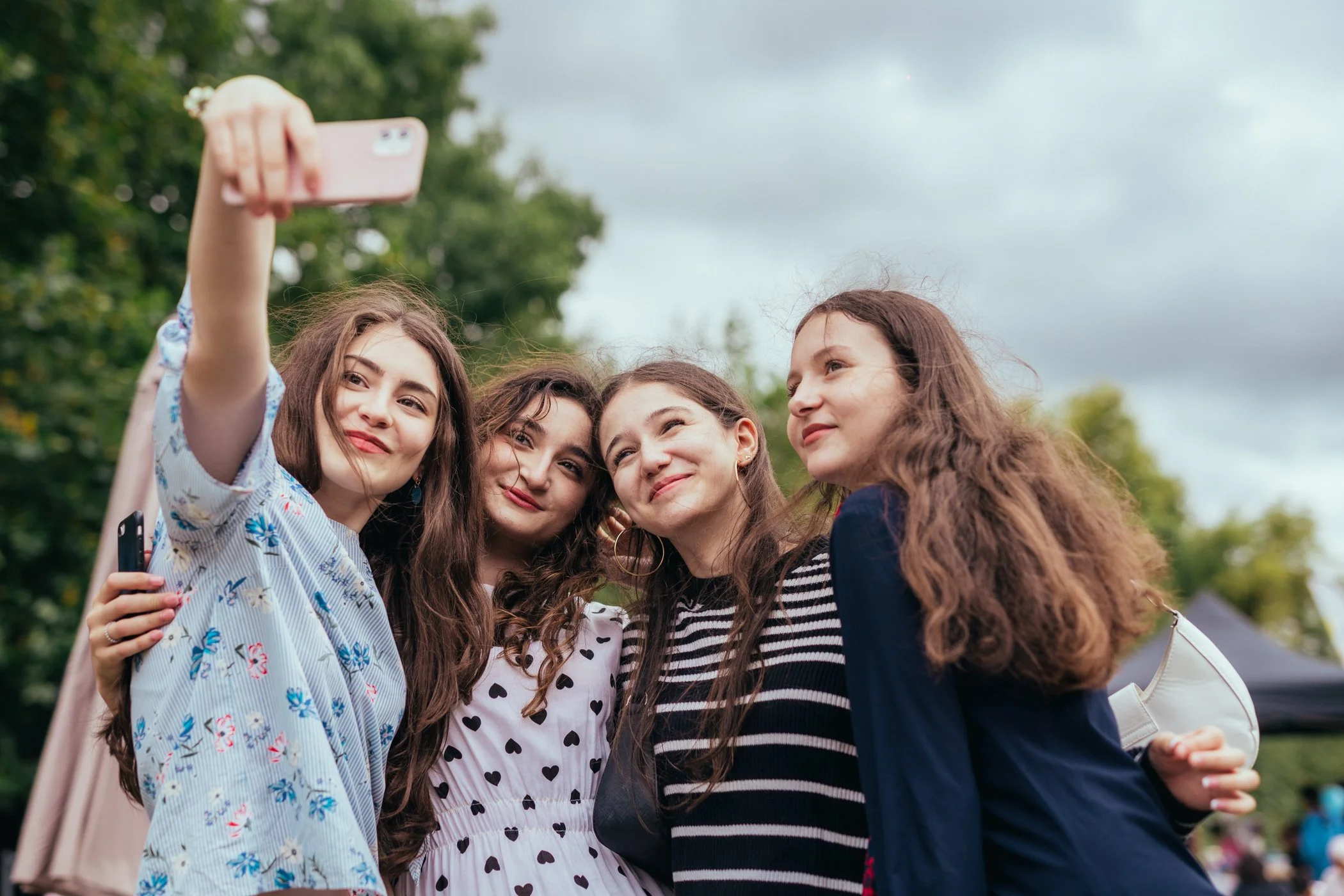 Vijf jonge vrouwen maken een selfie in een park.