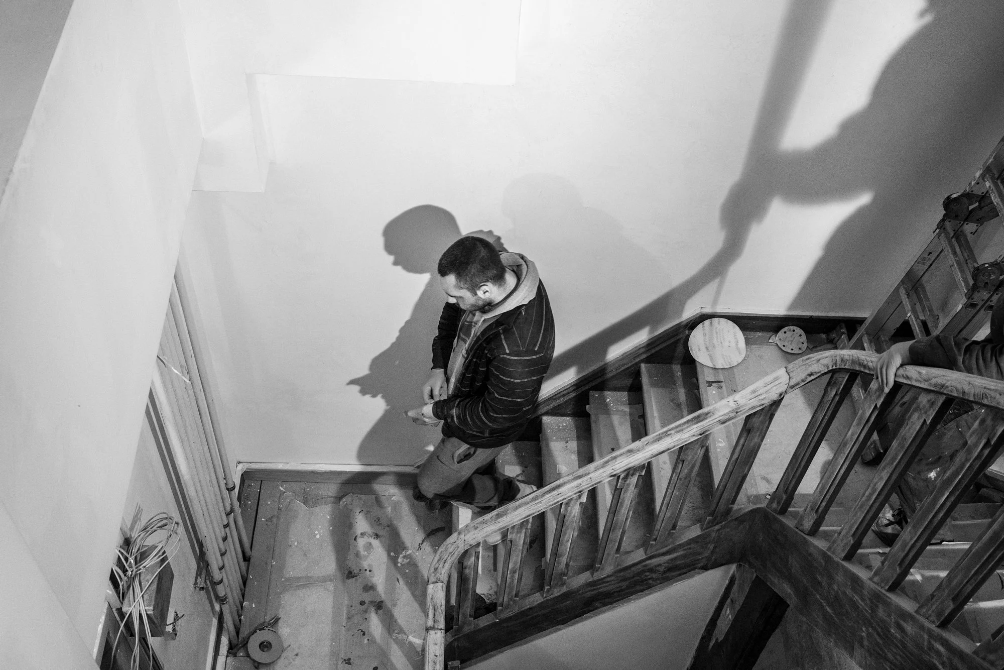 Man die op een trap staat in een interieur, met schaduwprojecties op de muur
