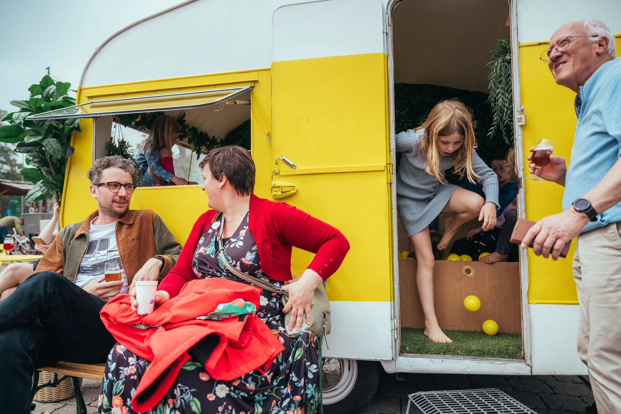 Gezinnen en kinderen genieten van een picknick en spelen in een gele foodtruck op een dag buiten.