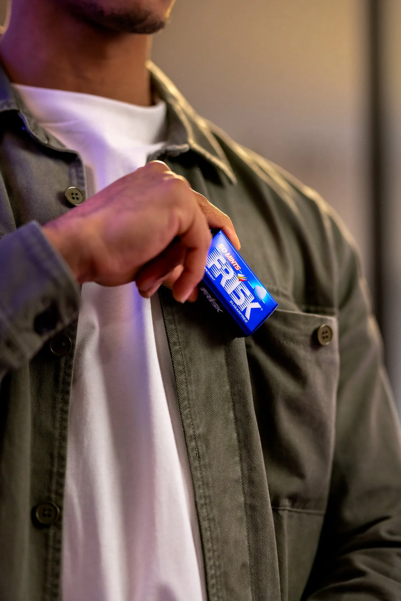 Persoon die een blue ESKY portable speaker uit een zak haalt, gekleed in een groene jas en een witte T-shirt.