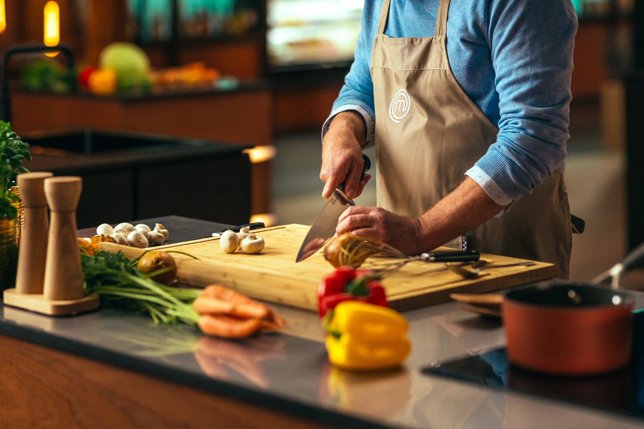 Persoon snijdt groenten in een keukenrestaurant met kookapparatuur.