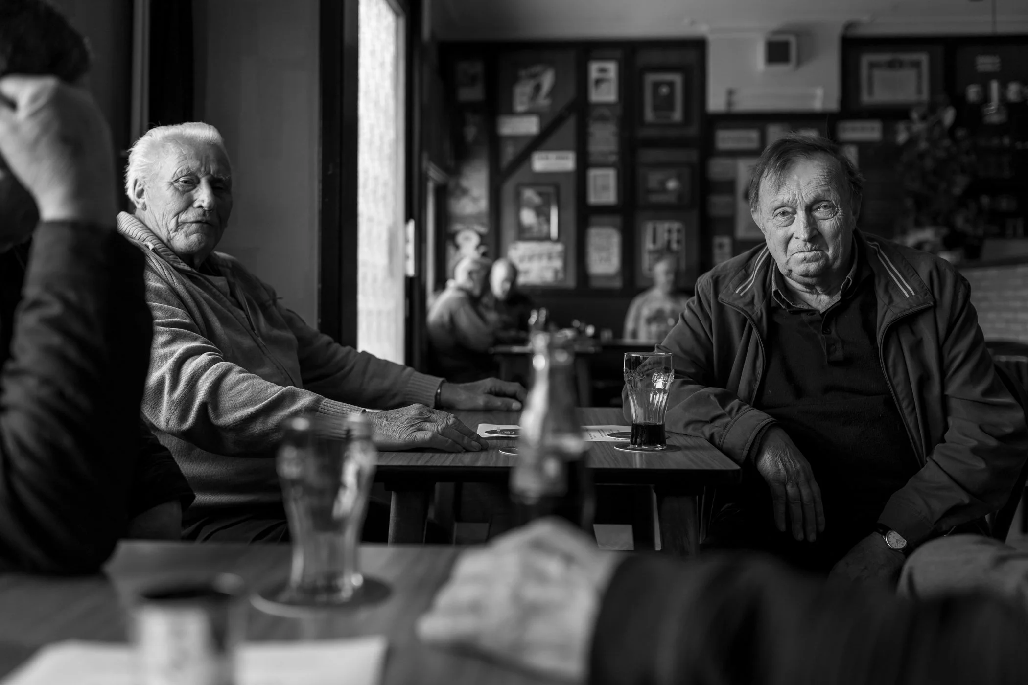 Gezicht van twee oudere mannen in een café, zwart-wit foto, rustige sfeer.
