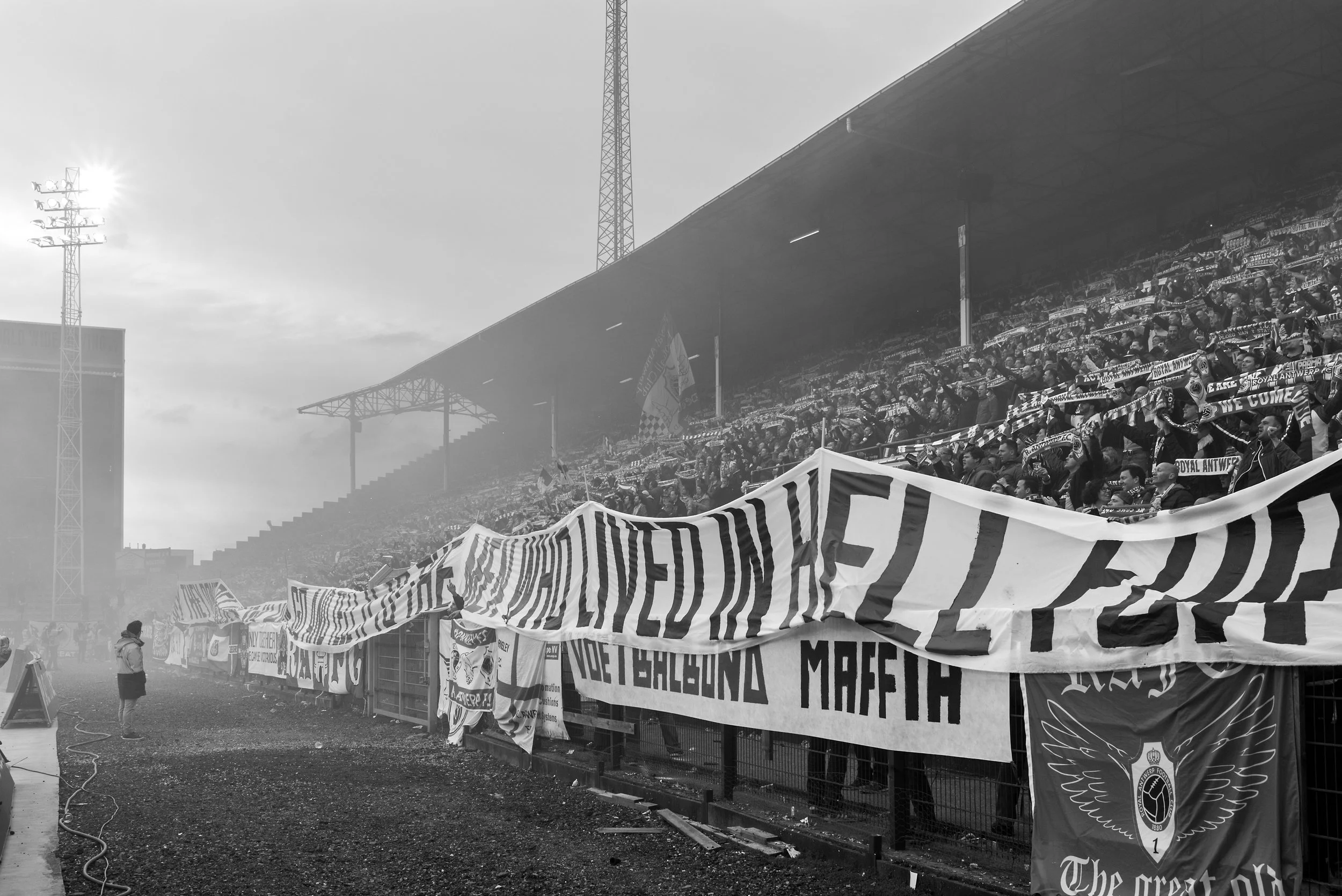 Fans die vlaggen en spandoeken vasthouden in een stadion tijdens een voetbalwedstrijd.
