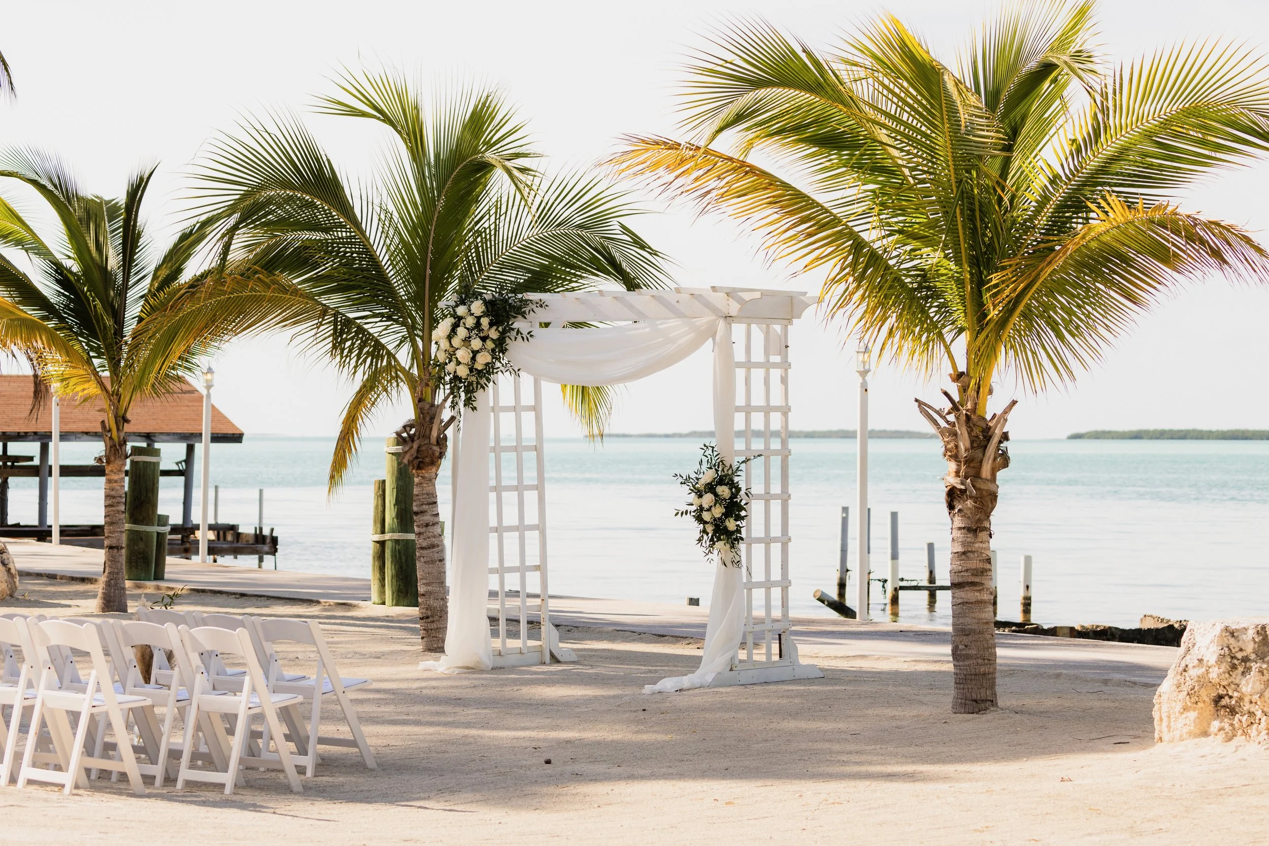 Outdoor beach wedding ceremony arch framed by two palm trees at Key Largo Lighthouse Beach Resort Florida Keys