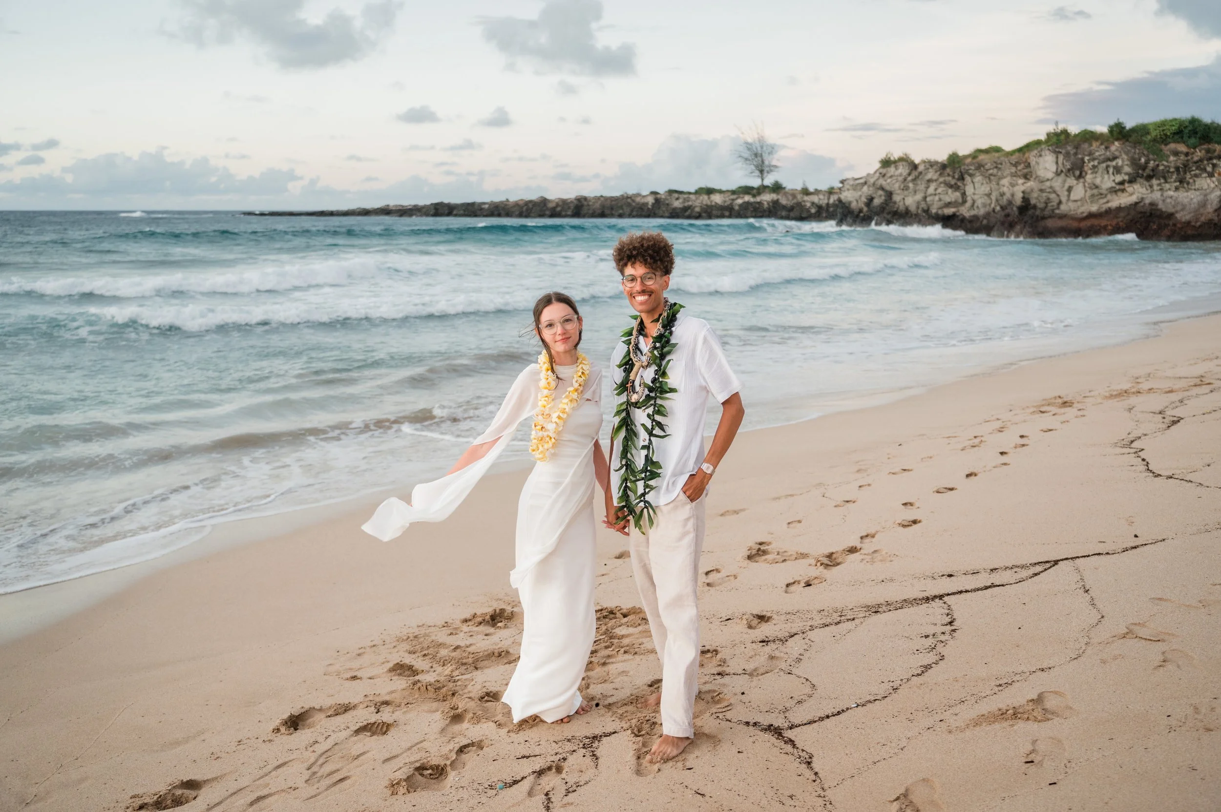 Couple standing on a Maui beach during an intimate elopement ceremony with ocean in the background