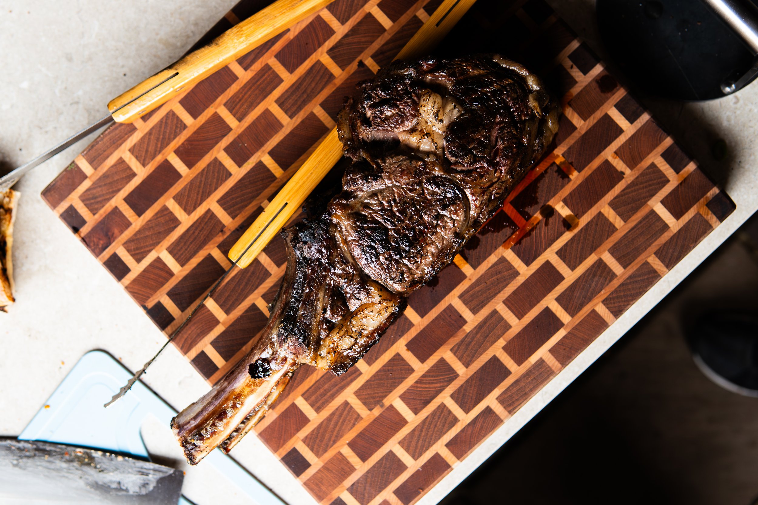 Cooked beef rib roast on a wooden cutting board with a bamboo skewer.
