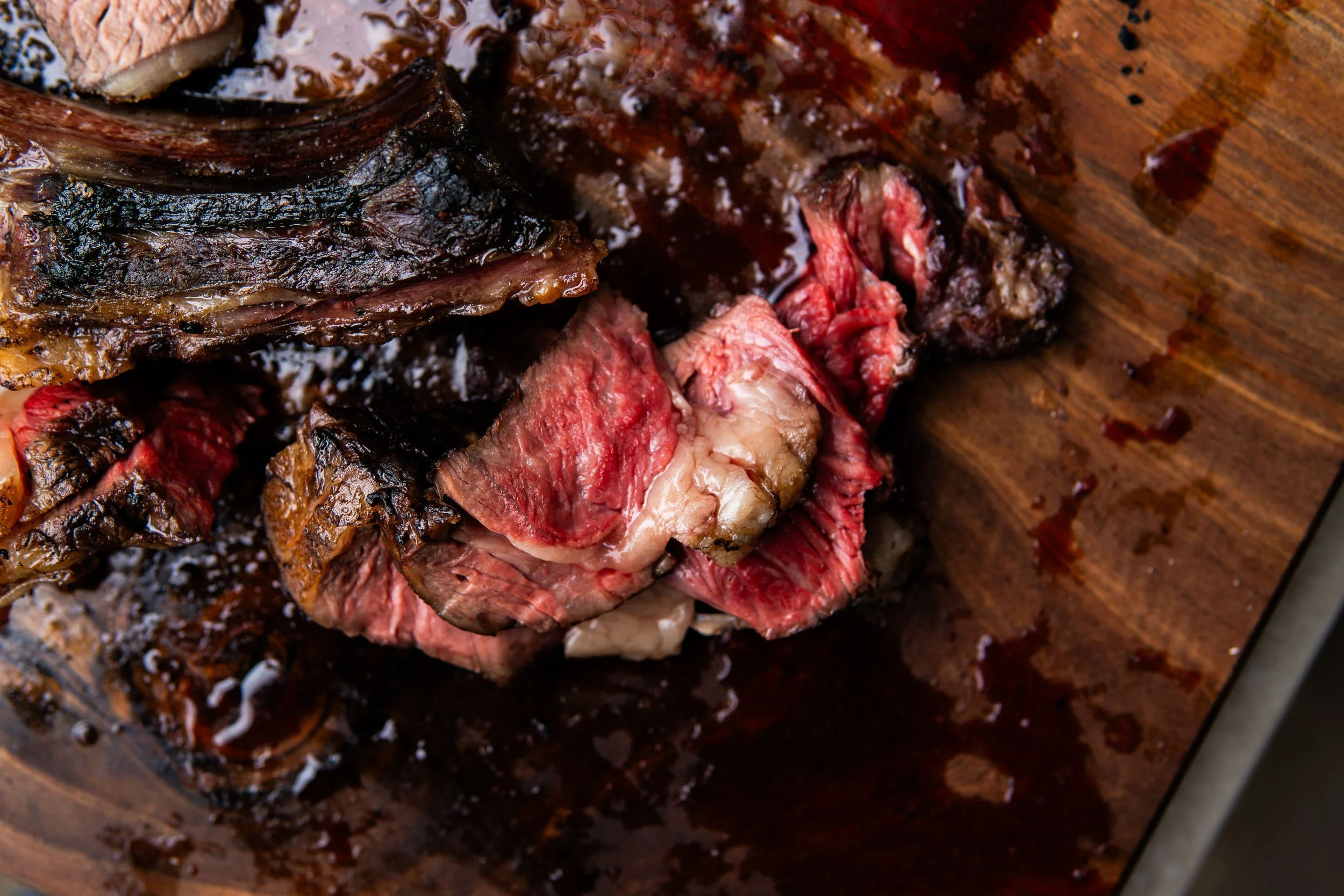 Close-up of a cooked, sliced steak on a wooden cutting board.
