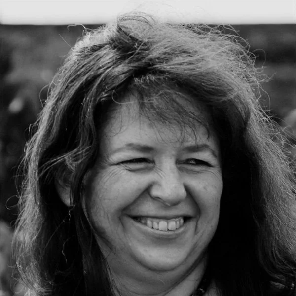 Femme souriante avec cheveux longs et épais, en noir et blanc.