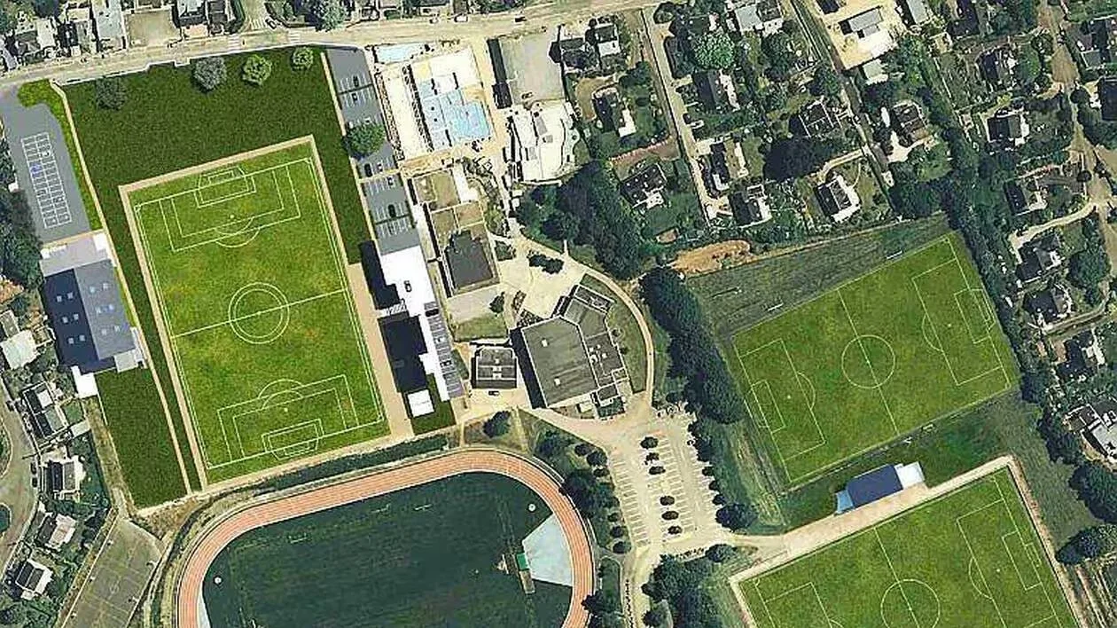 Vue aérienne d'un complexe sportif avec plusieurs terrains de soccer, une piste d'athlétisme, une piscine, et des bâtiments environnants, entouré par un quartier résidentiel.