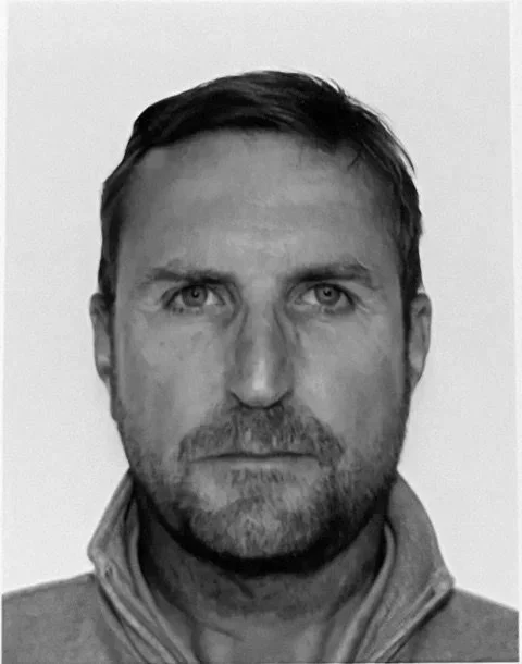 Portrait en noir et blanc d'un homme avec une veste zippée, regardant vers l'avant.