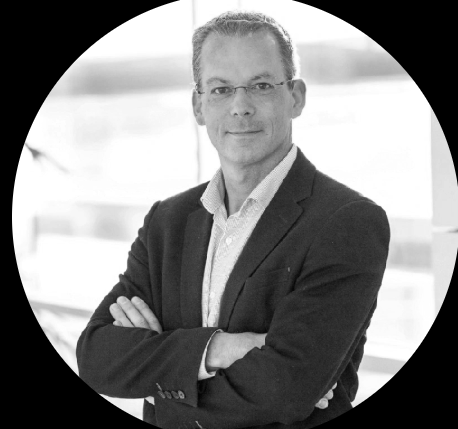 Homme d'affaires portant un costume, croisant les bras, dans un espace moderne