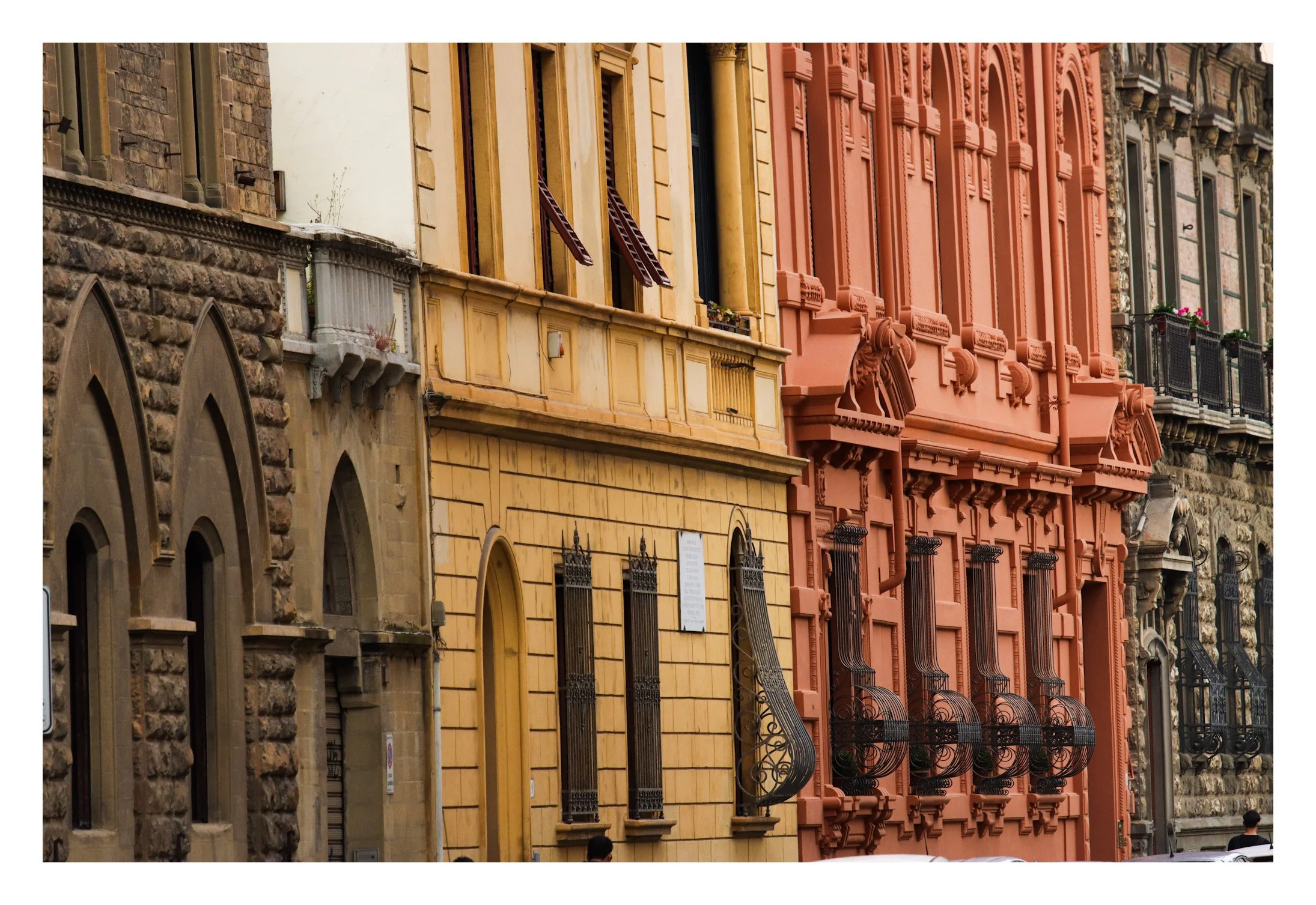 Colorful historic building facades with ornate ironwork and window details.
