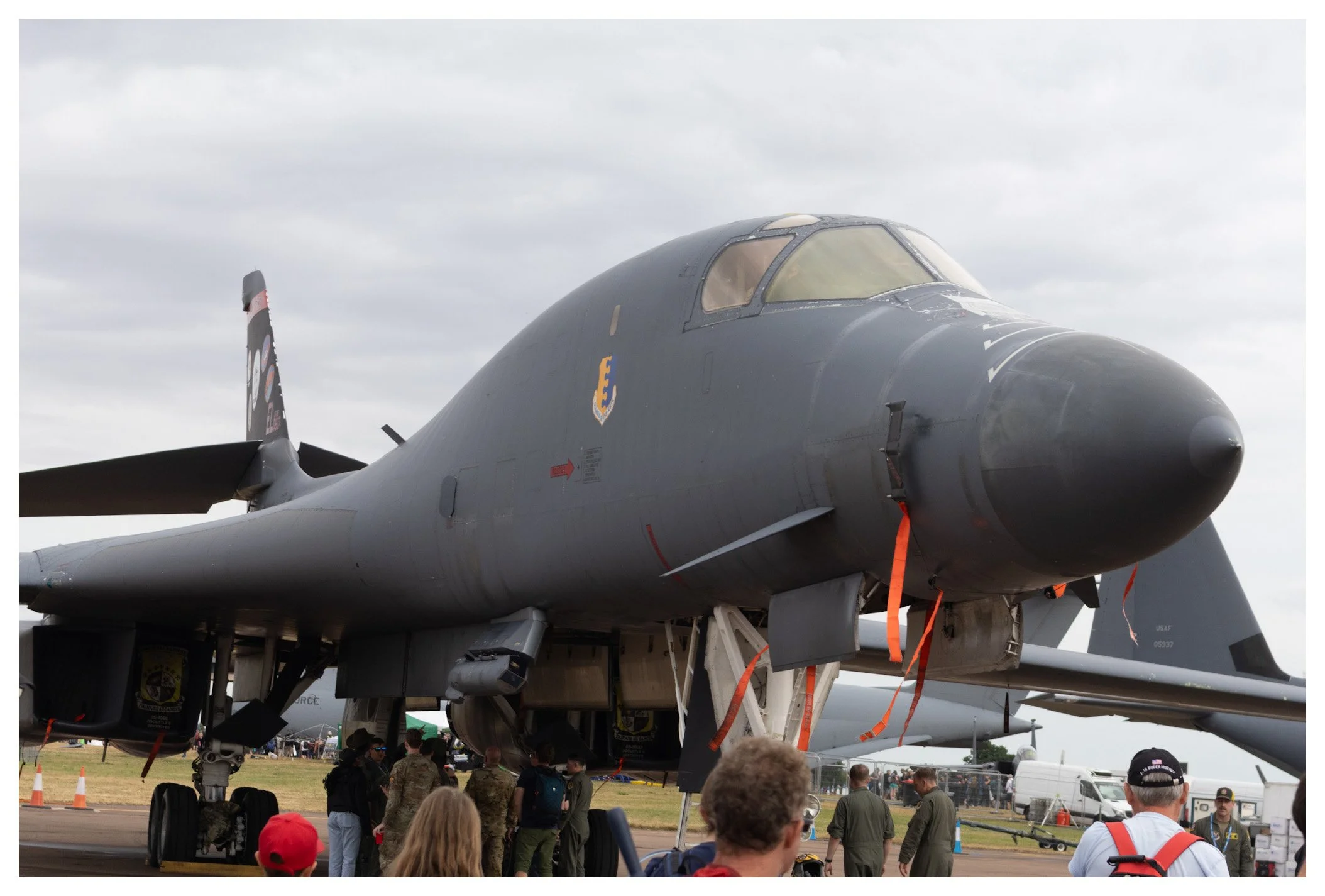 Military aircraft on display at an airshow with people and personnel walking around.