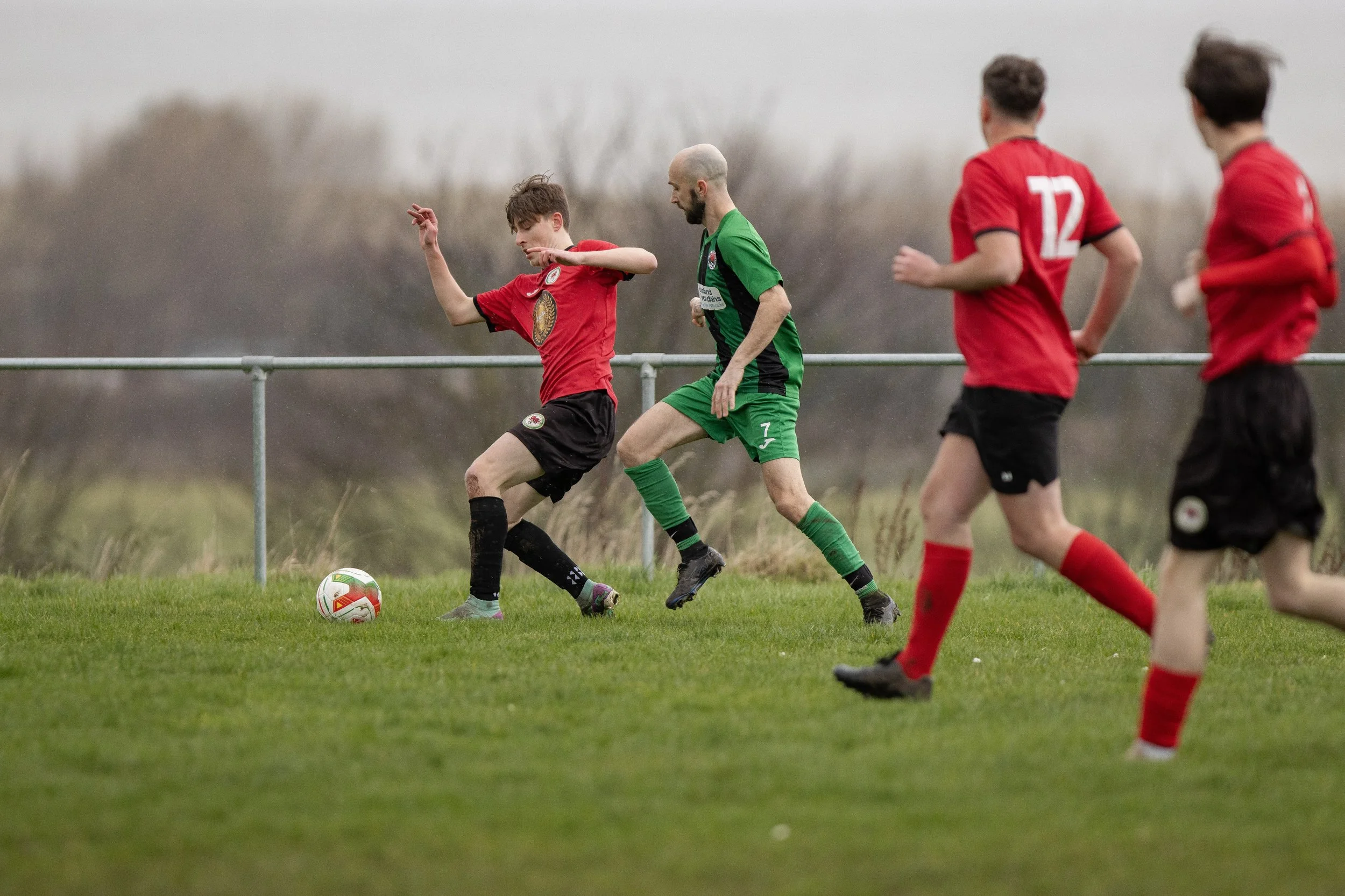 Youth soccer match with players in red and green uniforms on a grassy field