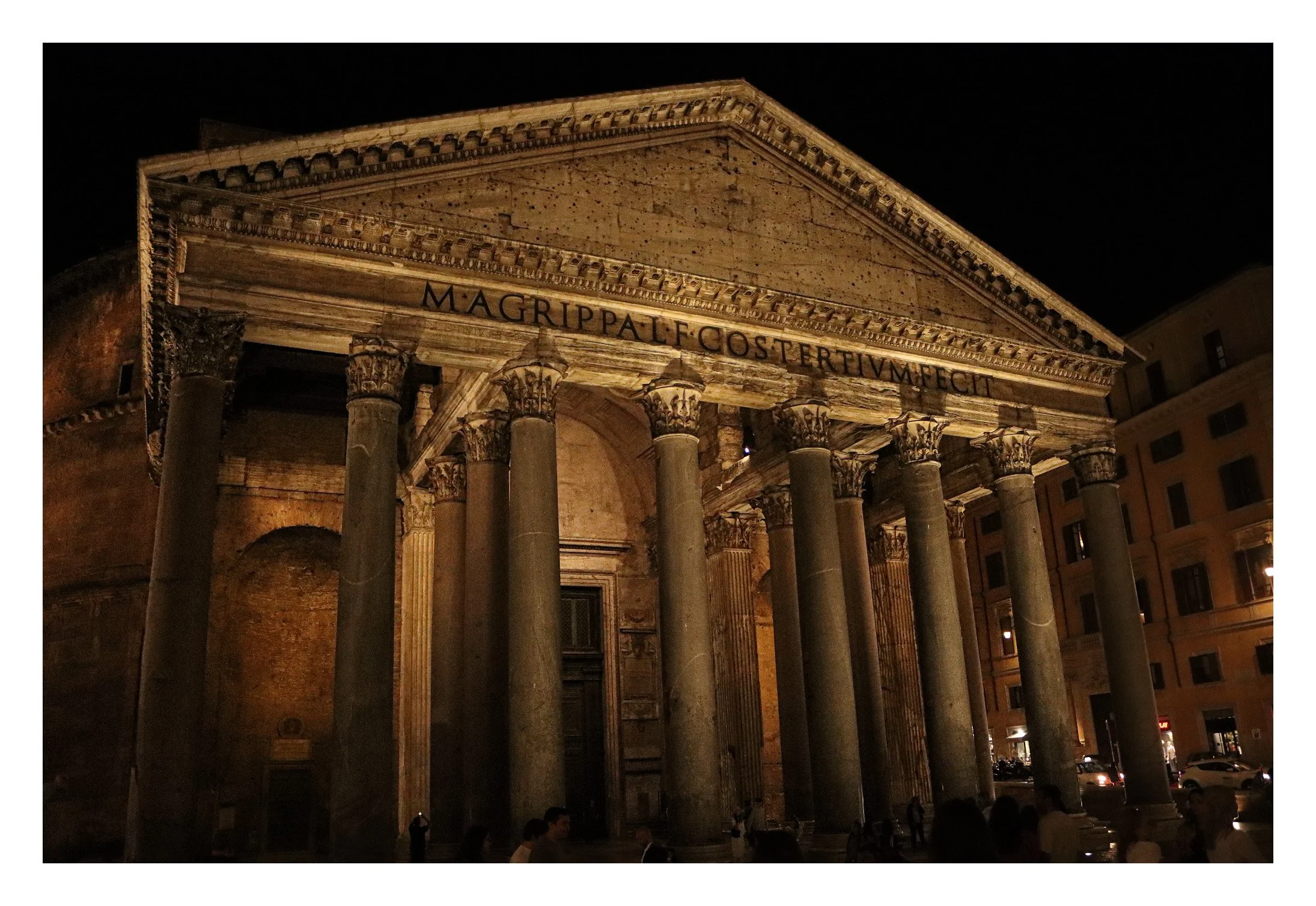 Night view of the ancient Roman Pantheon in Rome with tall columns and a triangular pediment, illuminated against a dark sky.