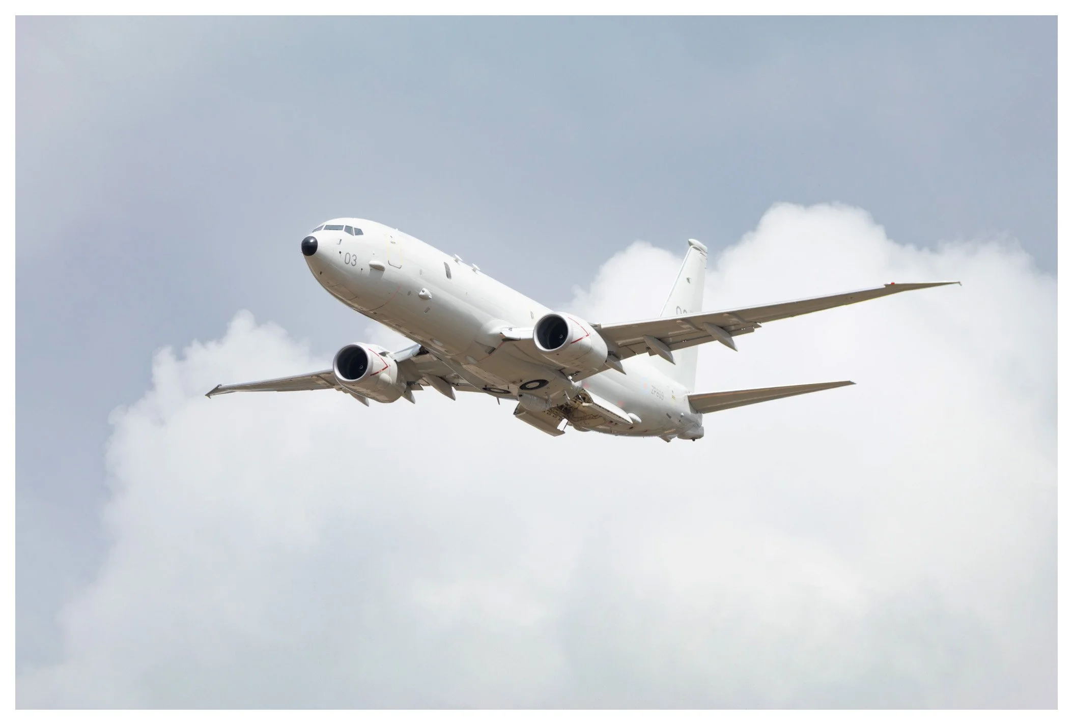 A white commercial airplane flying through a cloudy sky.