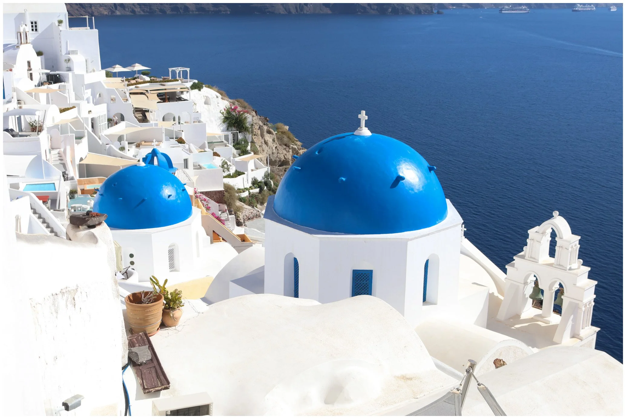 White buildings with blue domes in Santorini, Greece, overlooking the Aegean Sea.