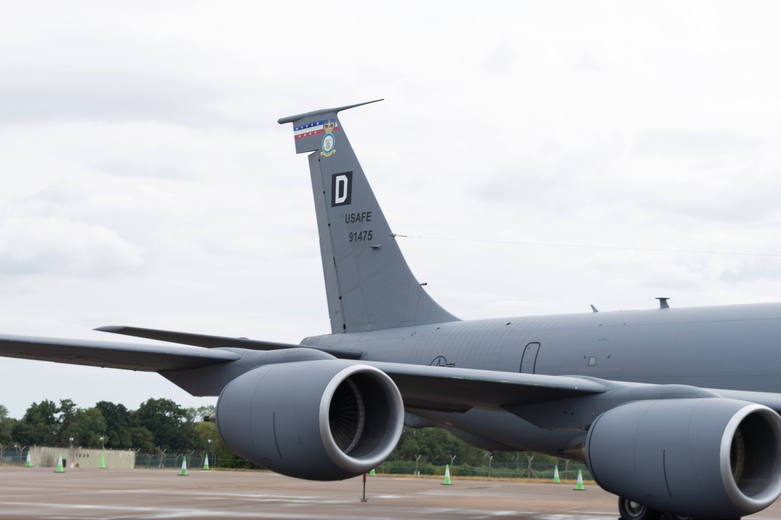 Close-up of a military aircraft's tail and engines on the tarmac at an airfield.