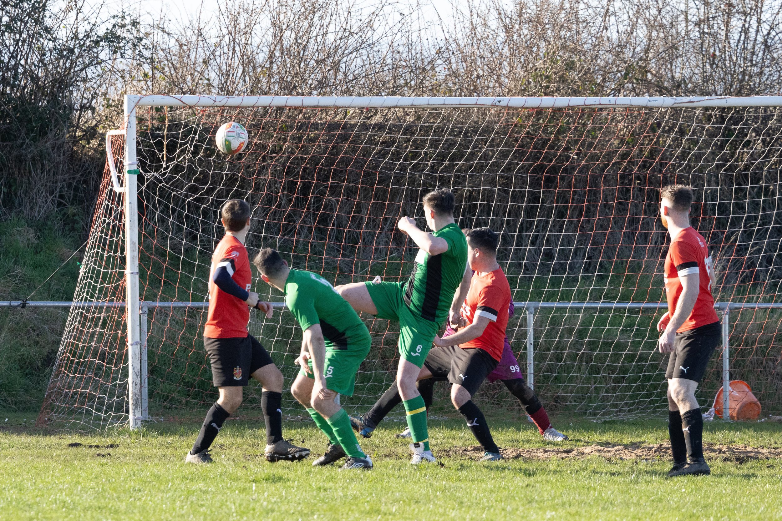 Soccer players competing for a header near the goal during a game