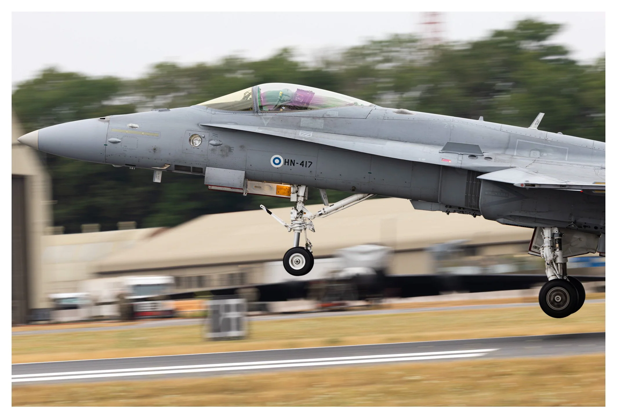 Fighter jet aircraft taking off from runway with blurred background.