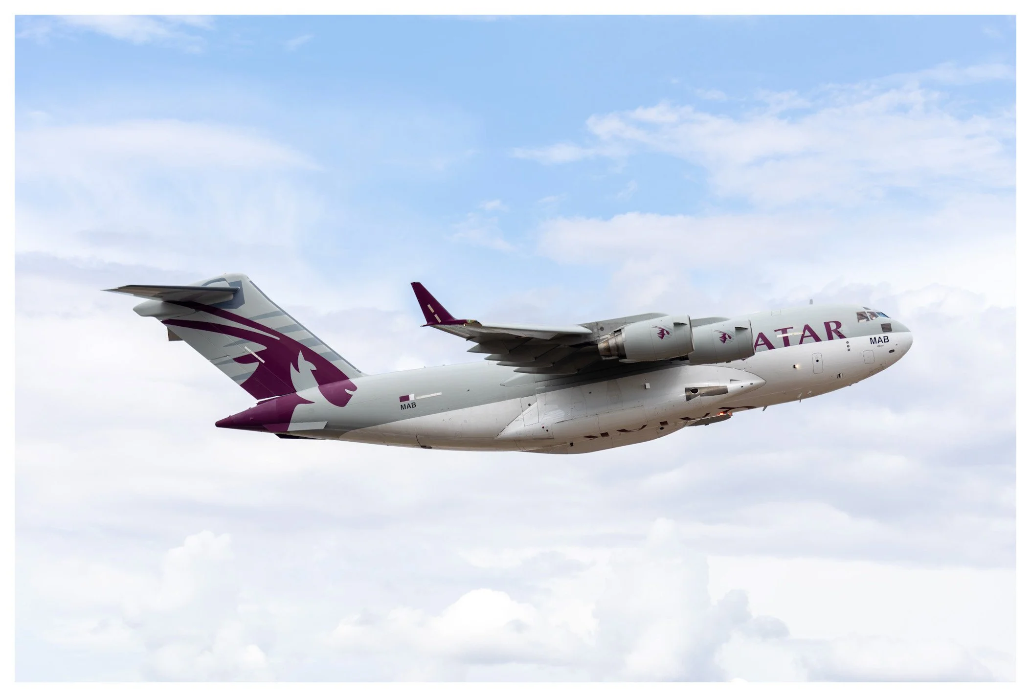 Qatar Airways cargo airplane flying in the sky with clouds.