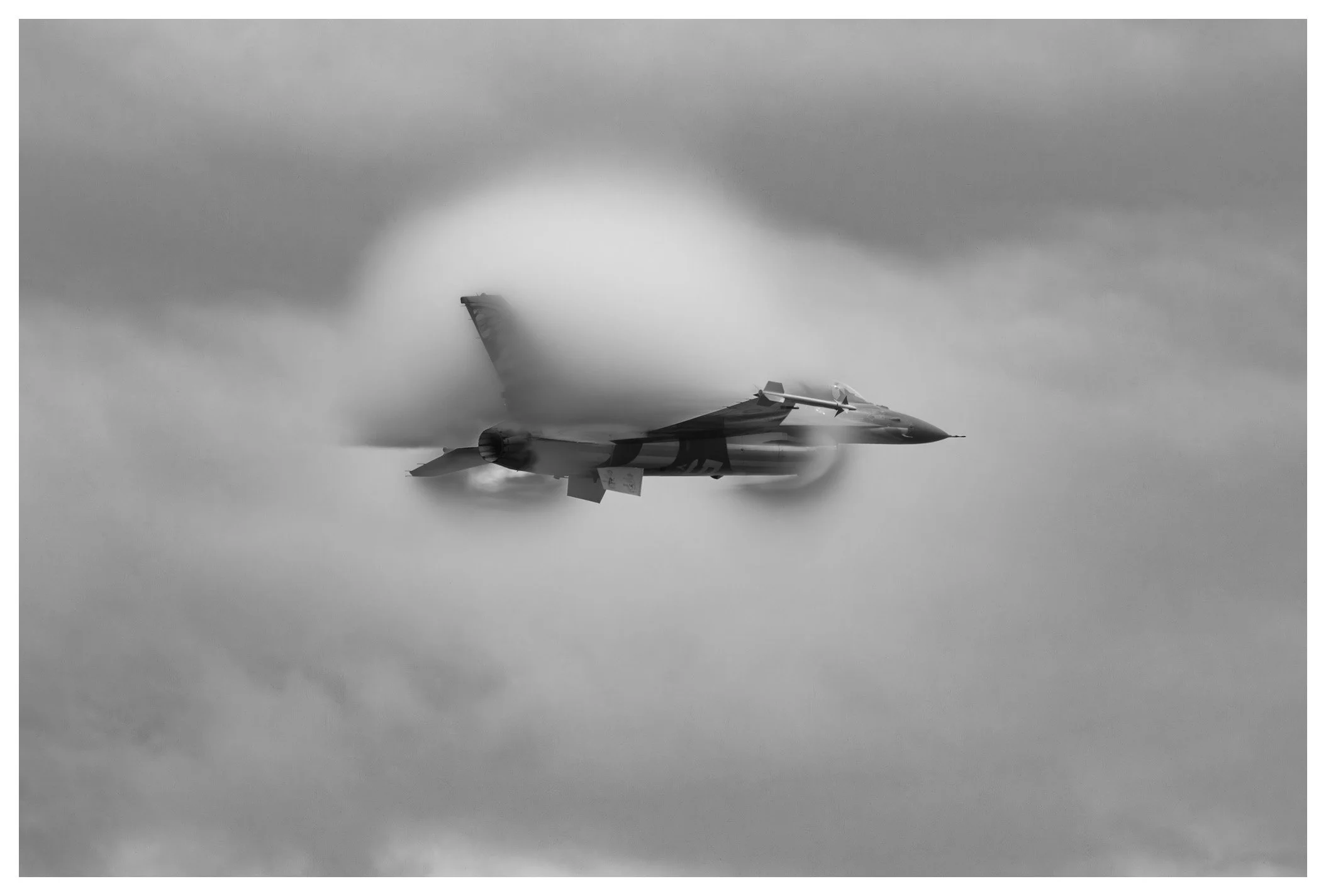 A fighter jet flying at high speed through the clouds, with motion blur and vapor trails.