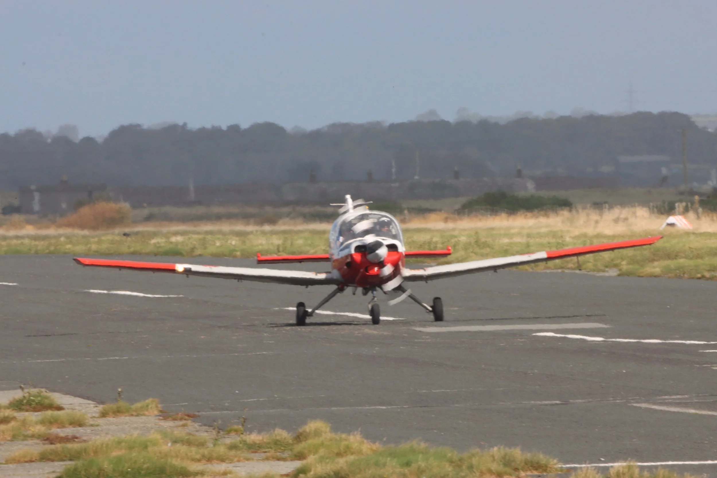 Small red and white airplane on runway.