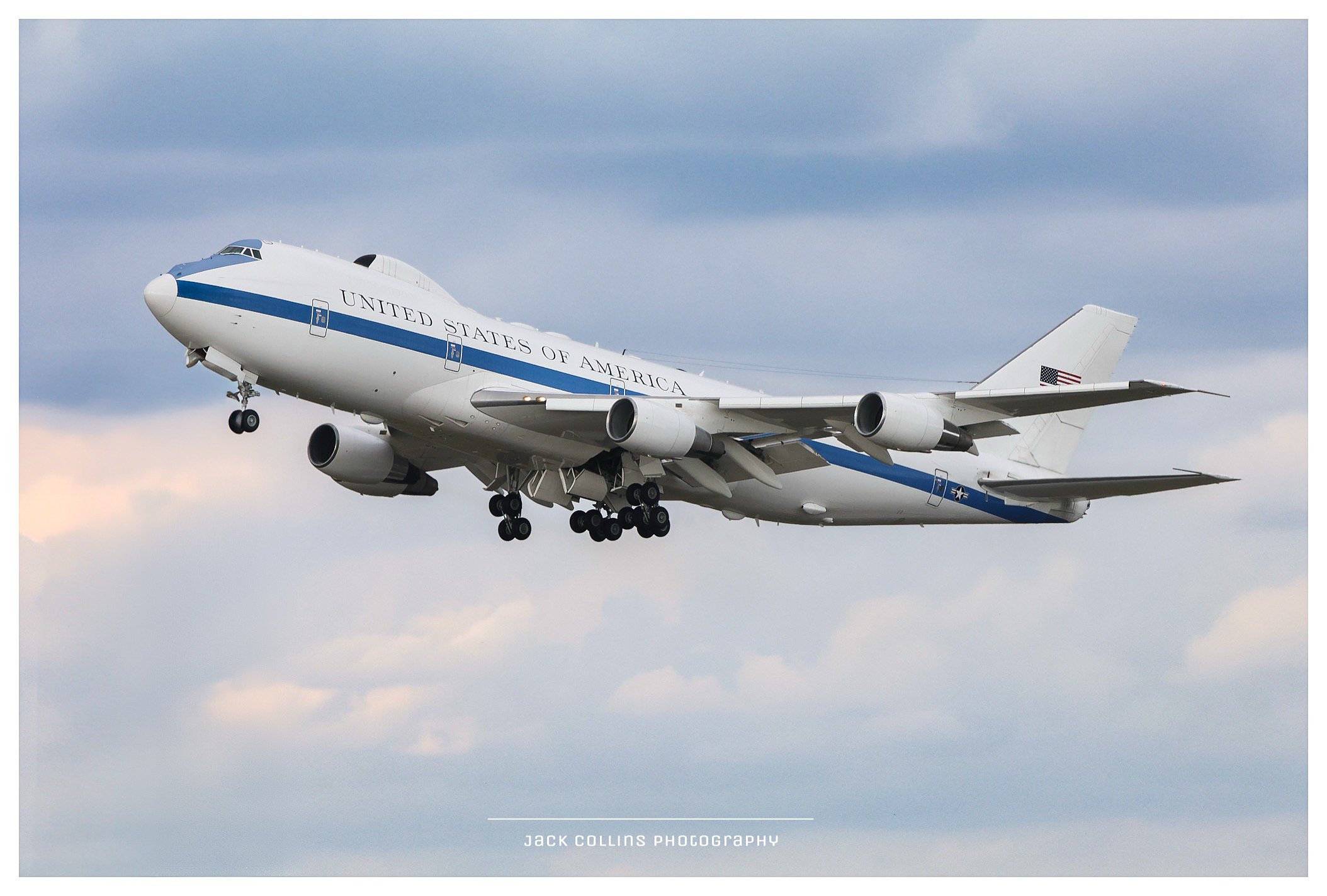 A United States Air Force Boeing C-17 Globemaster III cargo aircraft in flight against a cloudy sky, with landing gear extended and engines running.