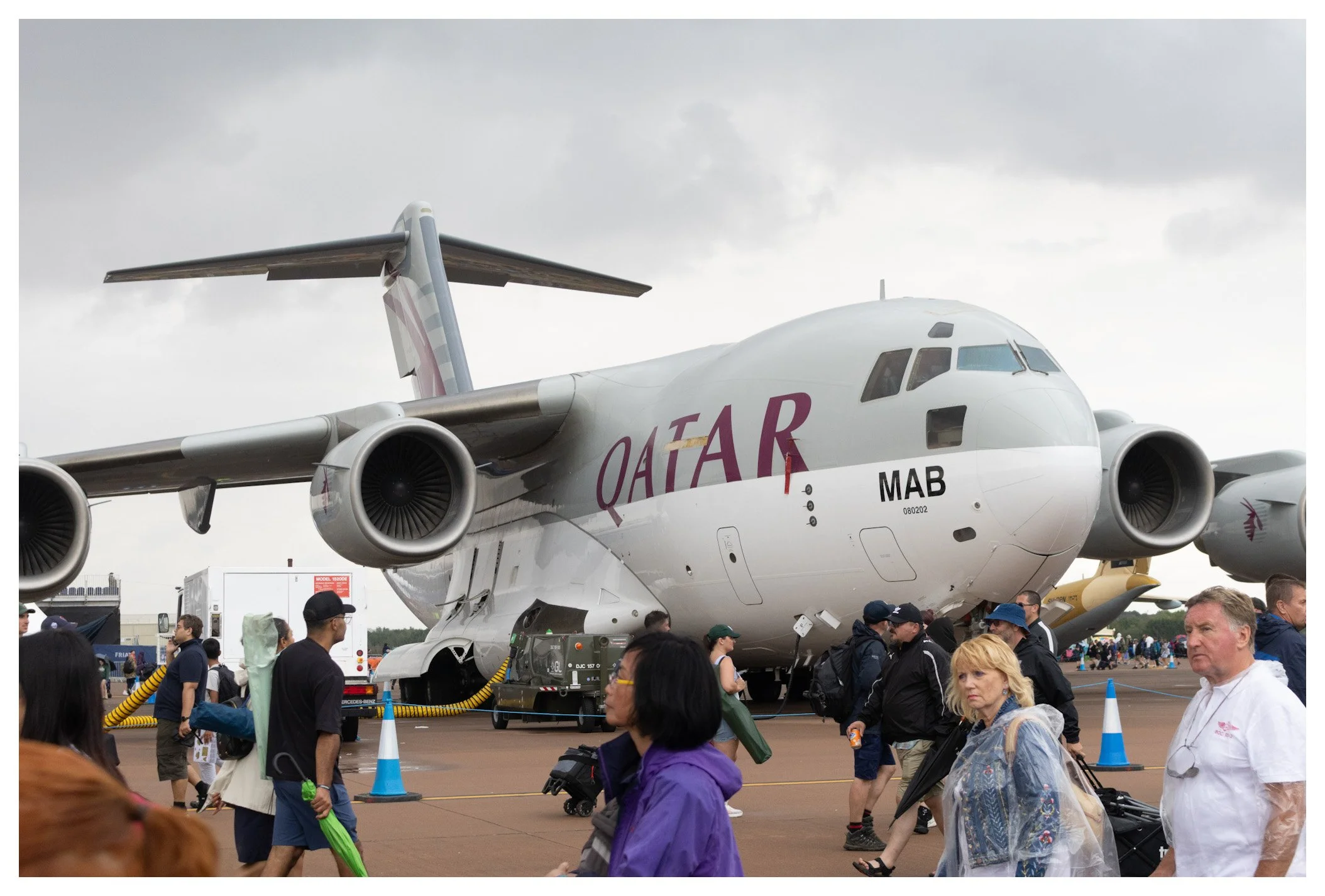 Qatar Airways cargo airplane displayed at an airshow, with people walking around it on a cloudy day.