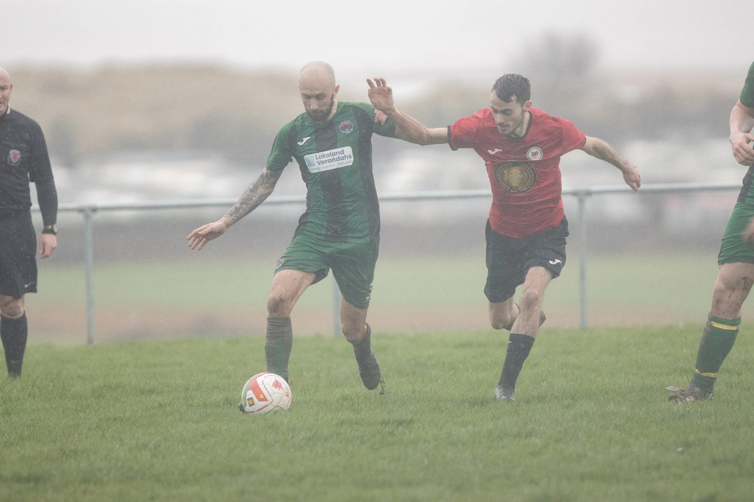 Soccer players competing in a rainy match on a wet field.