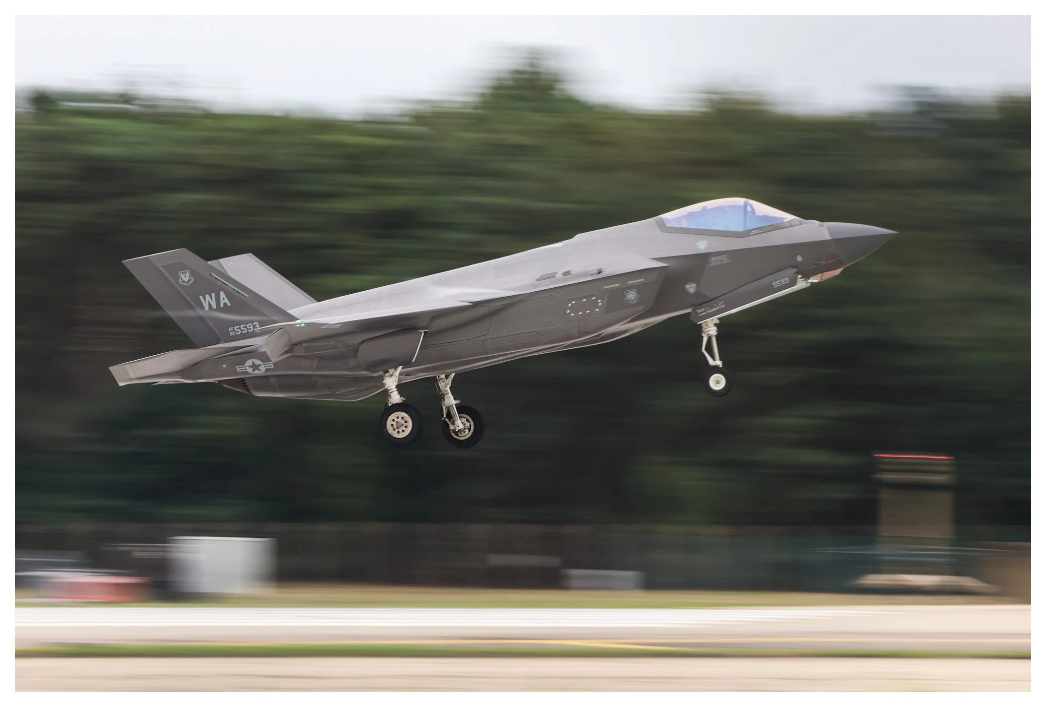 A military fighter jet taking off from the runway with blurred background.