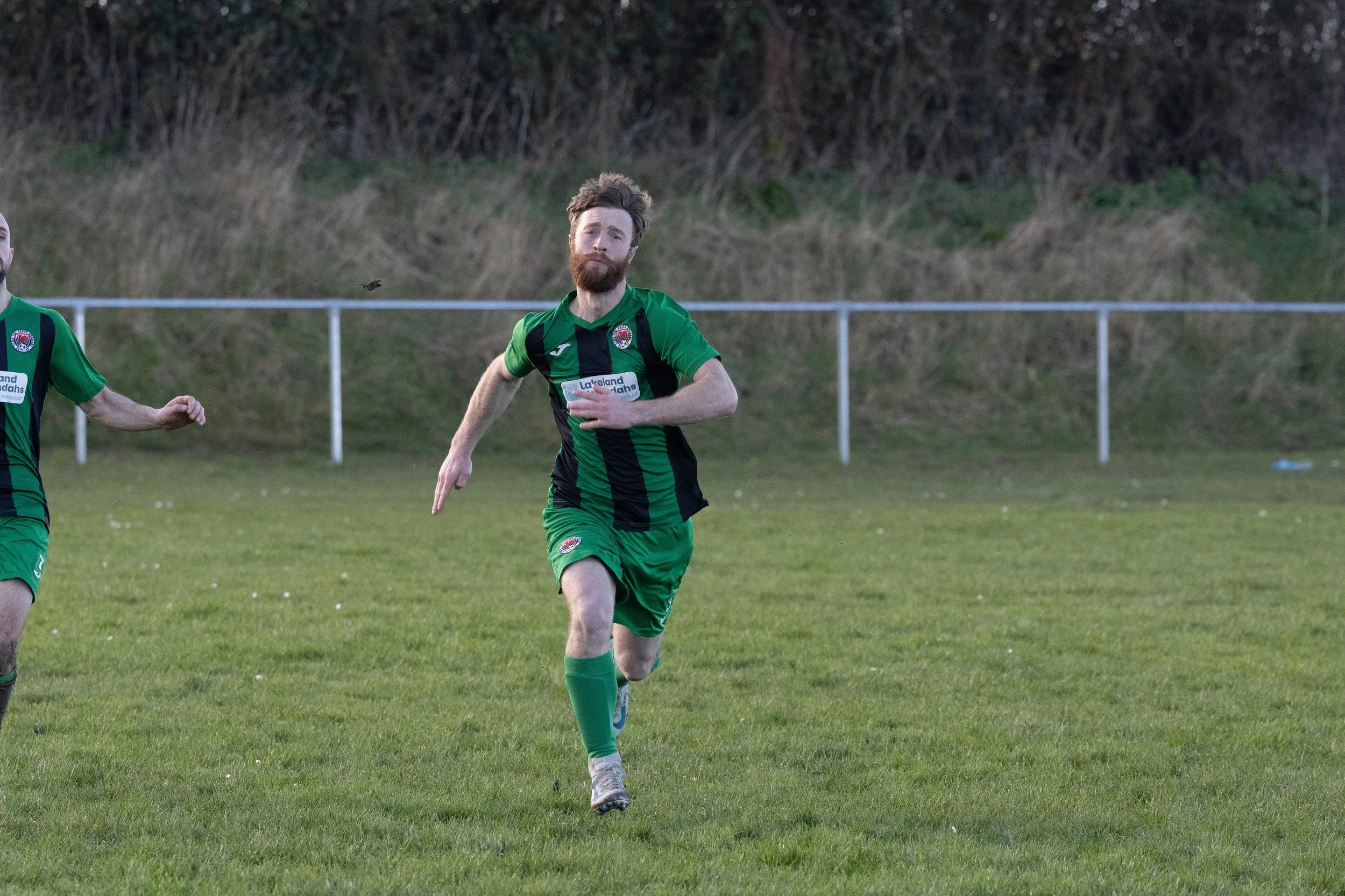 Soccer player in green uniform running on the field during a game.