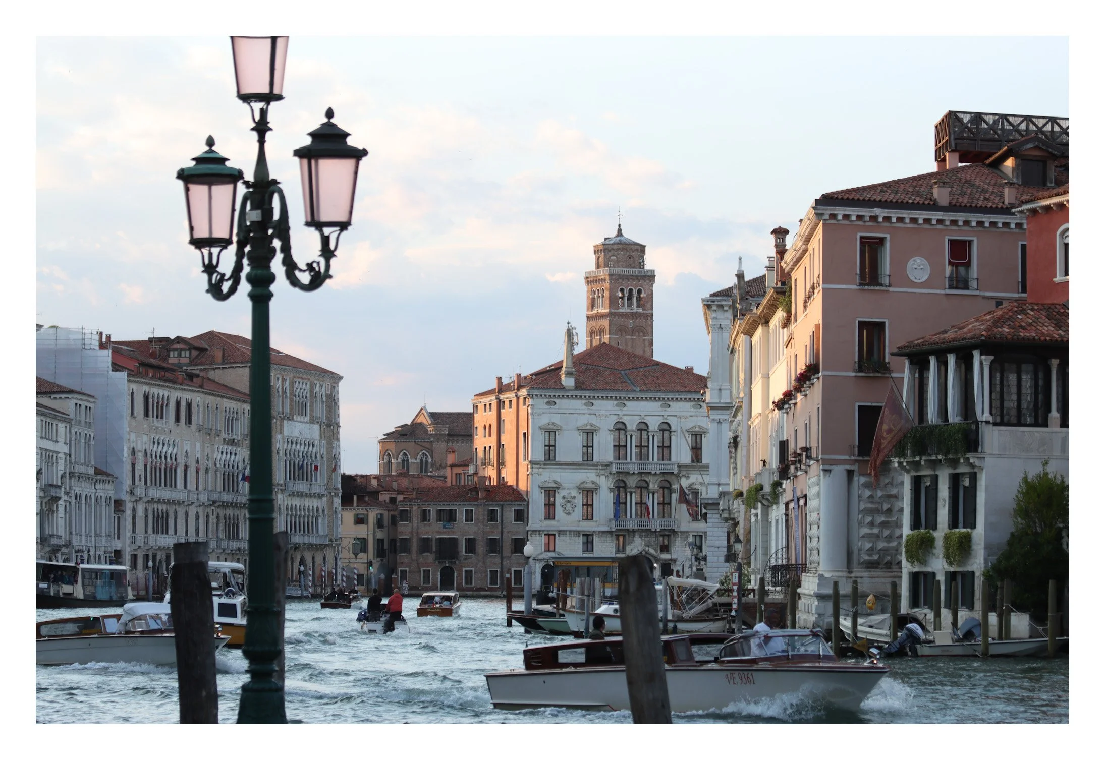 Venetian canal scene with boats, historic buildings, and a lamp post