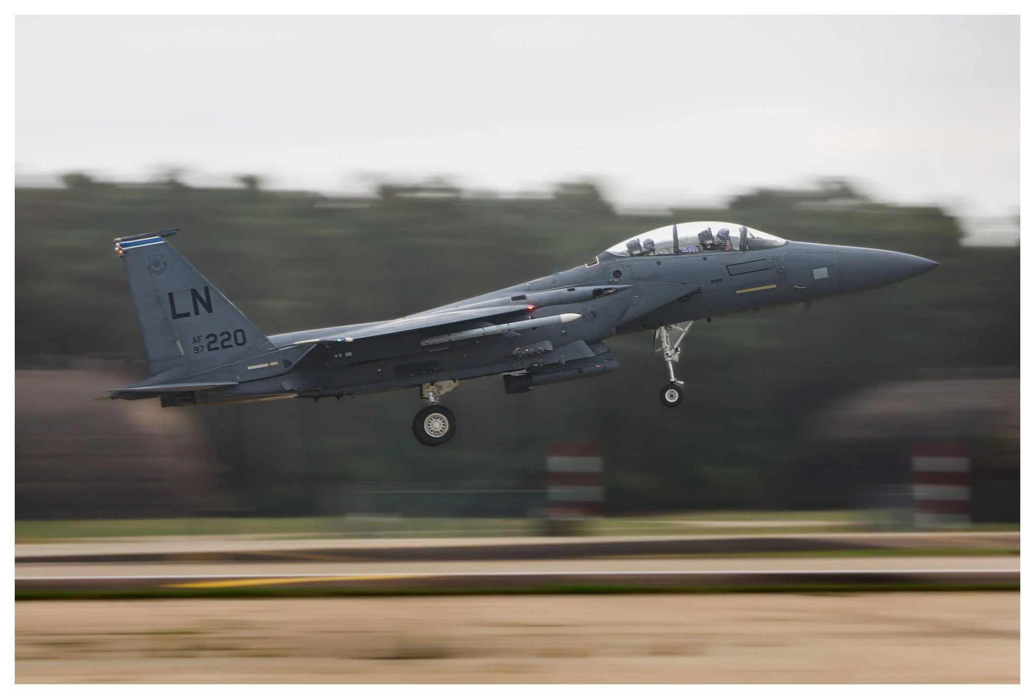 A military fighter jet airplane taking off from a runway at high speed.
