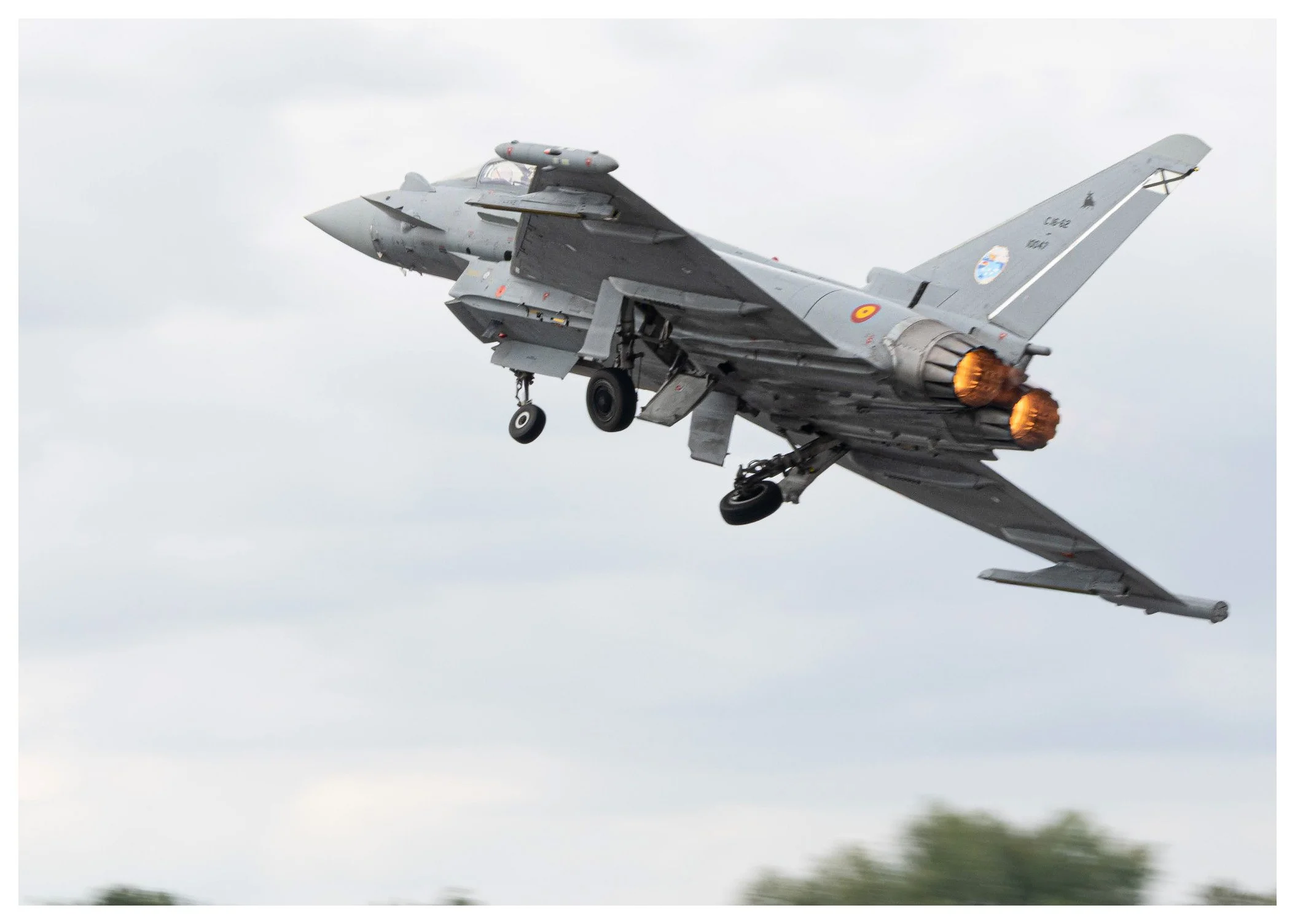 A military fighter jet aircraft flying in the sky with afterburners firing.