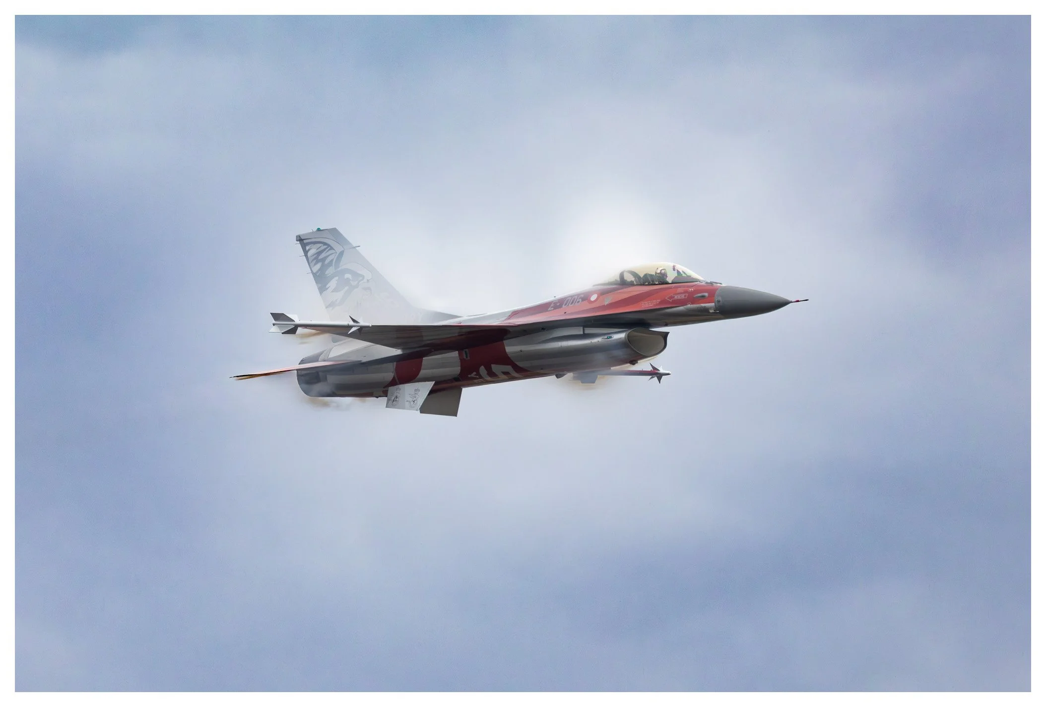 A fighter jet flying through the cloudy sky.