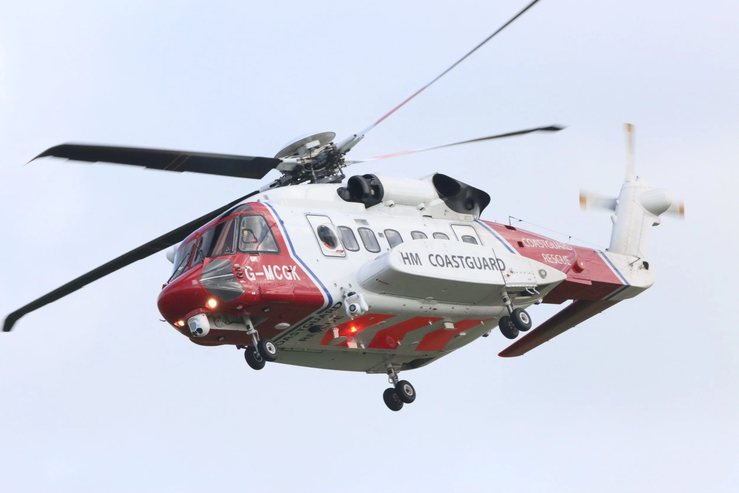 A helicopter marked with HM Coastguard, flying in the sky.