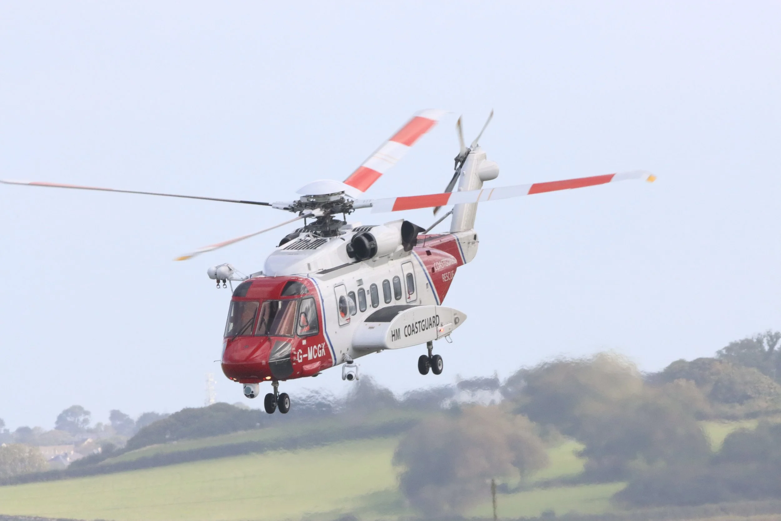A rescue helicopter flying low over a green landscape