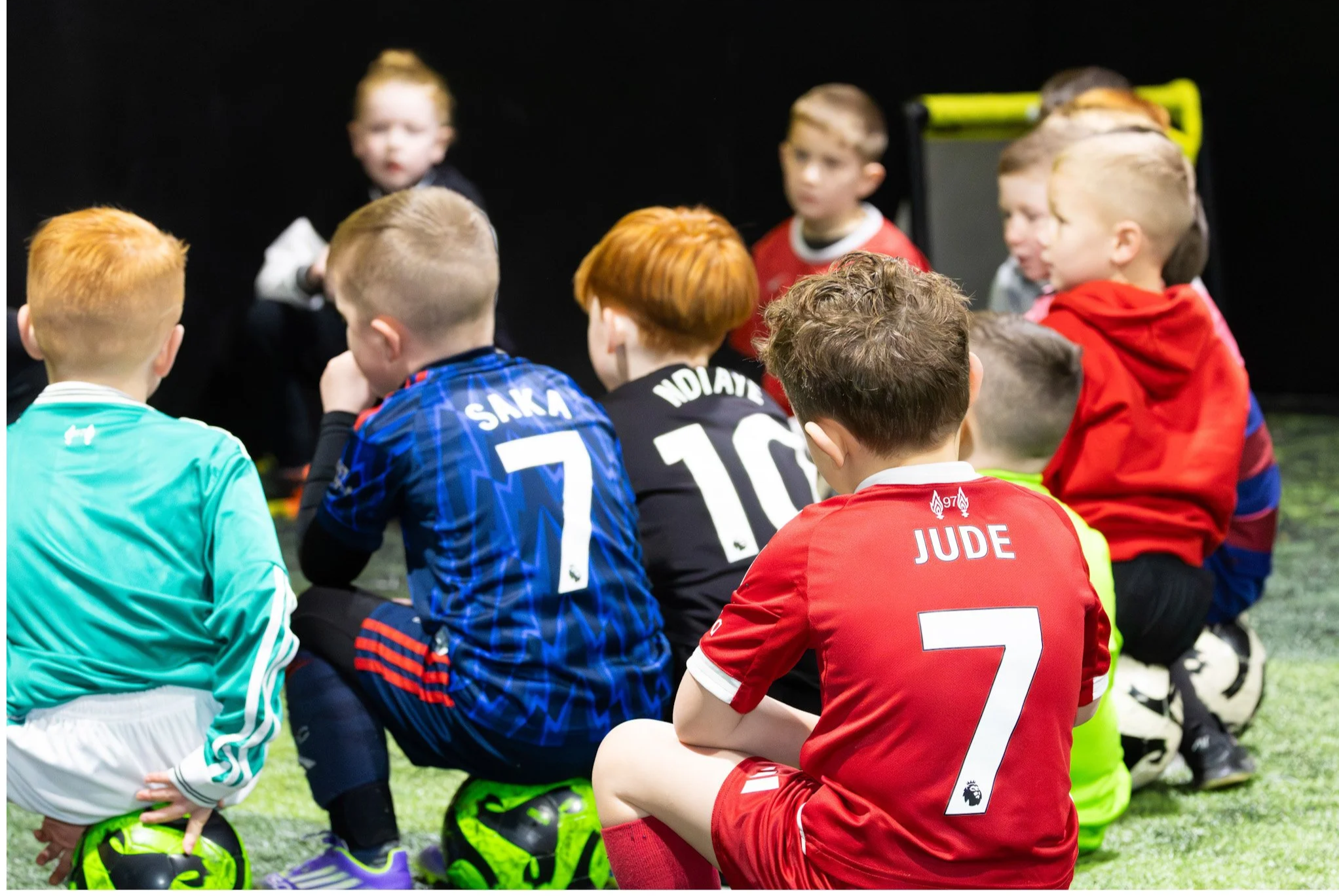 Young man with tattoos on arm, sitting on a bench on the sidewalk, vaping with smoke coming from mouth, wearing gray T-shirt, black jeans, and sneakers, in an urban street scene.
