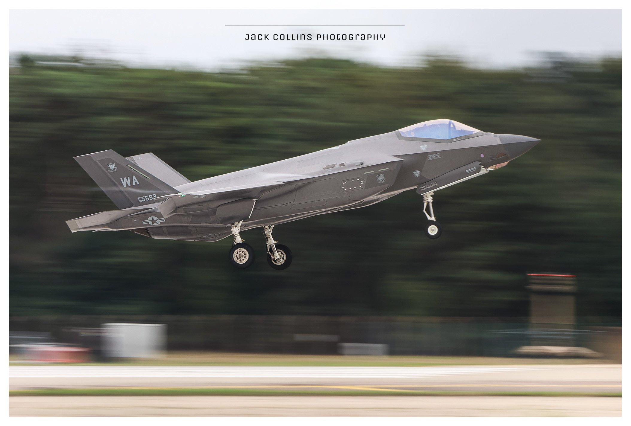 A military fighter jet takes off from a runway, with blurred background indicating speed.