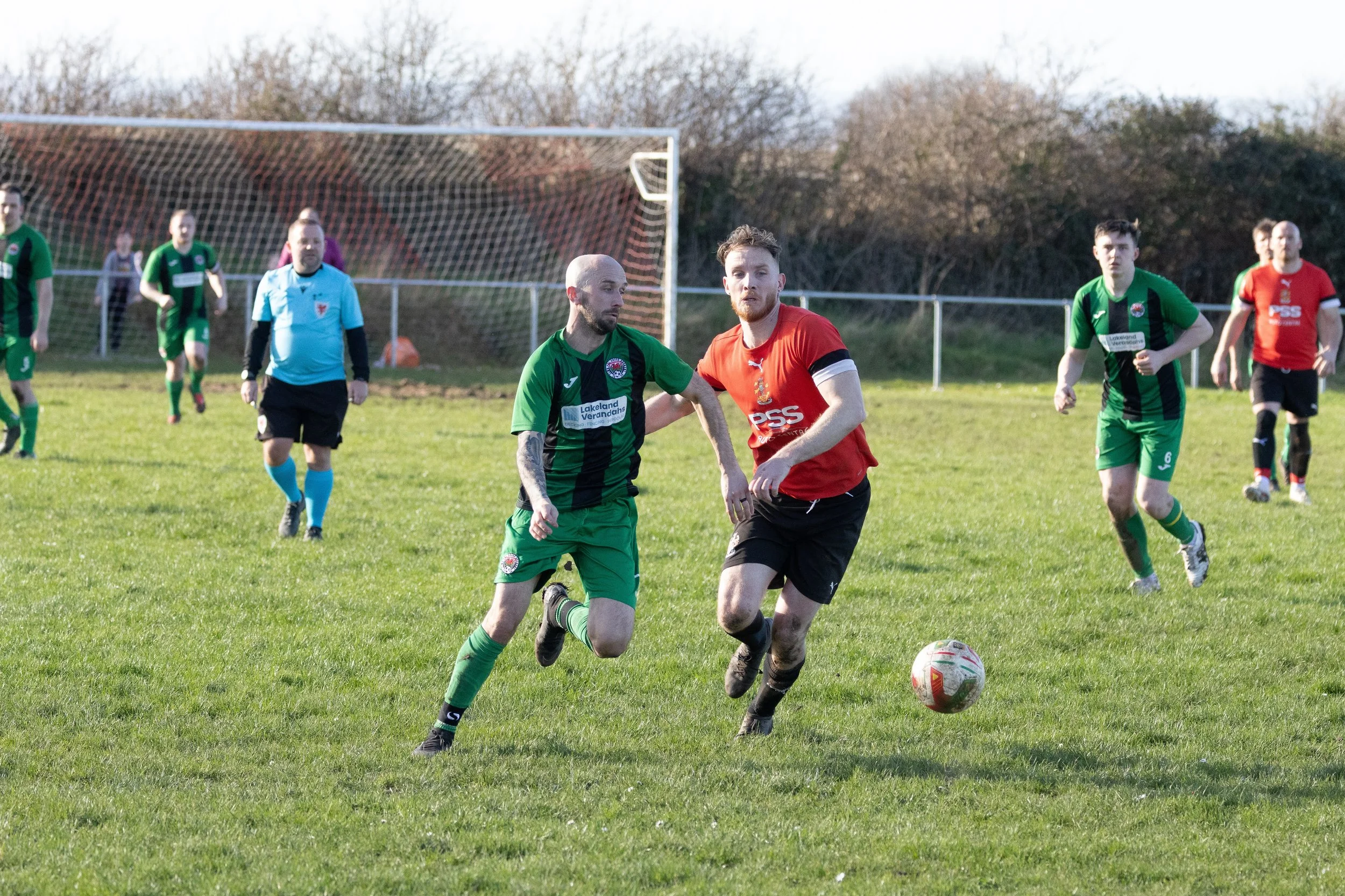 Soccer match with players in green and red jerseys competing on a grassy field