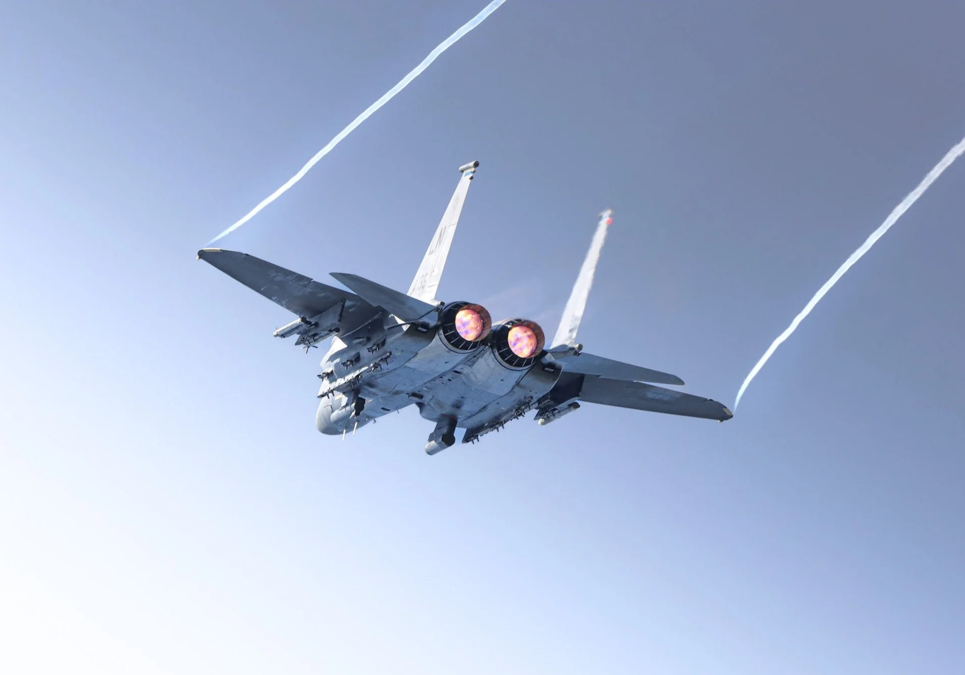 Fighter jet plane flying in the sky, with afterburners lit, leaving contrails behind.