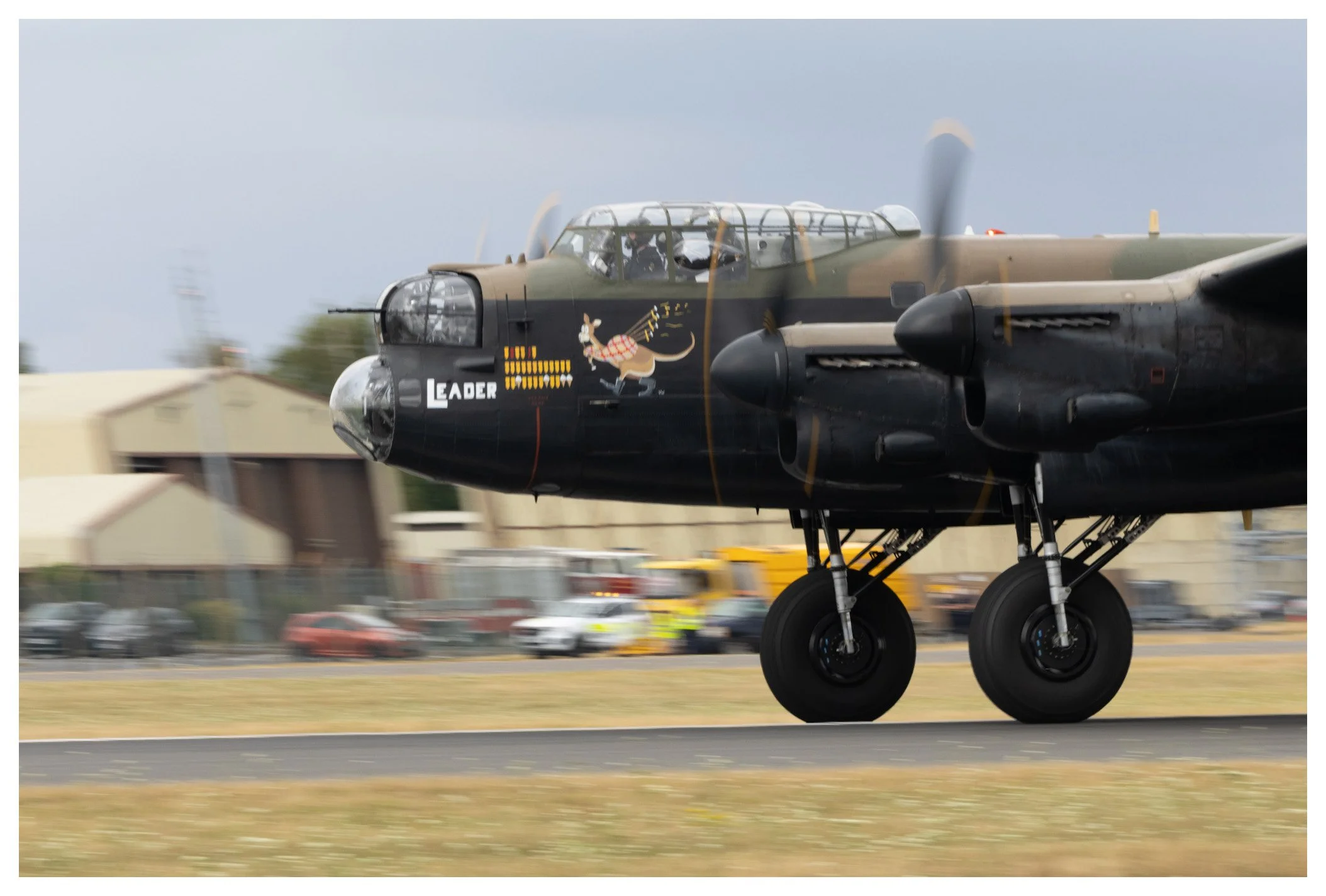 A military aircraft with a cartoon illustration of a rabbit on its nose, name 'LEADER' written on the fuselage, in motion on a runway.