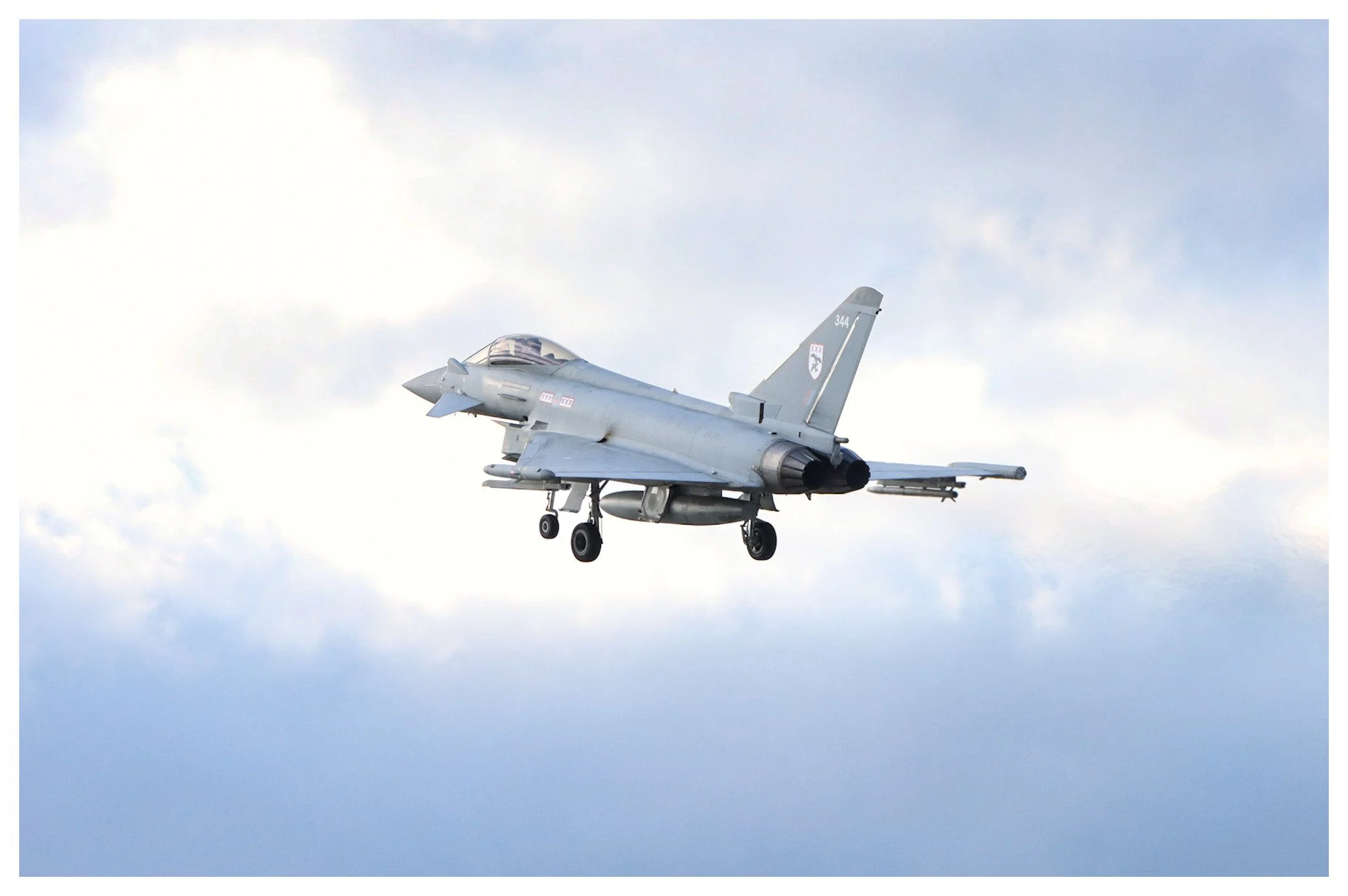 A fighter jet aircraft flying in a cloudy sky.