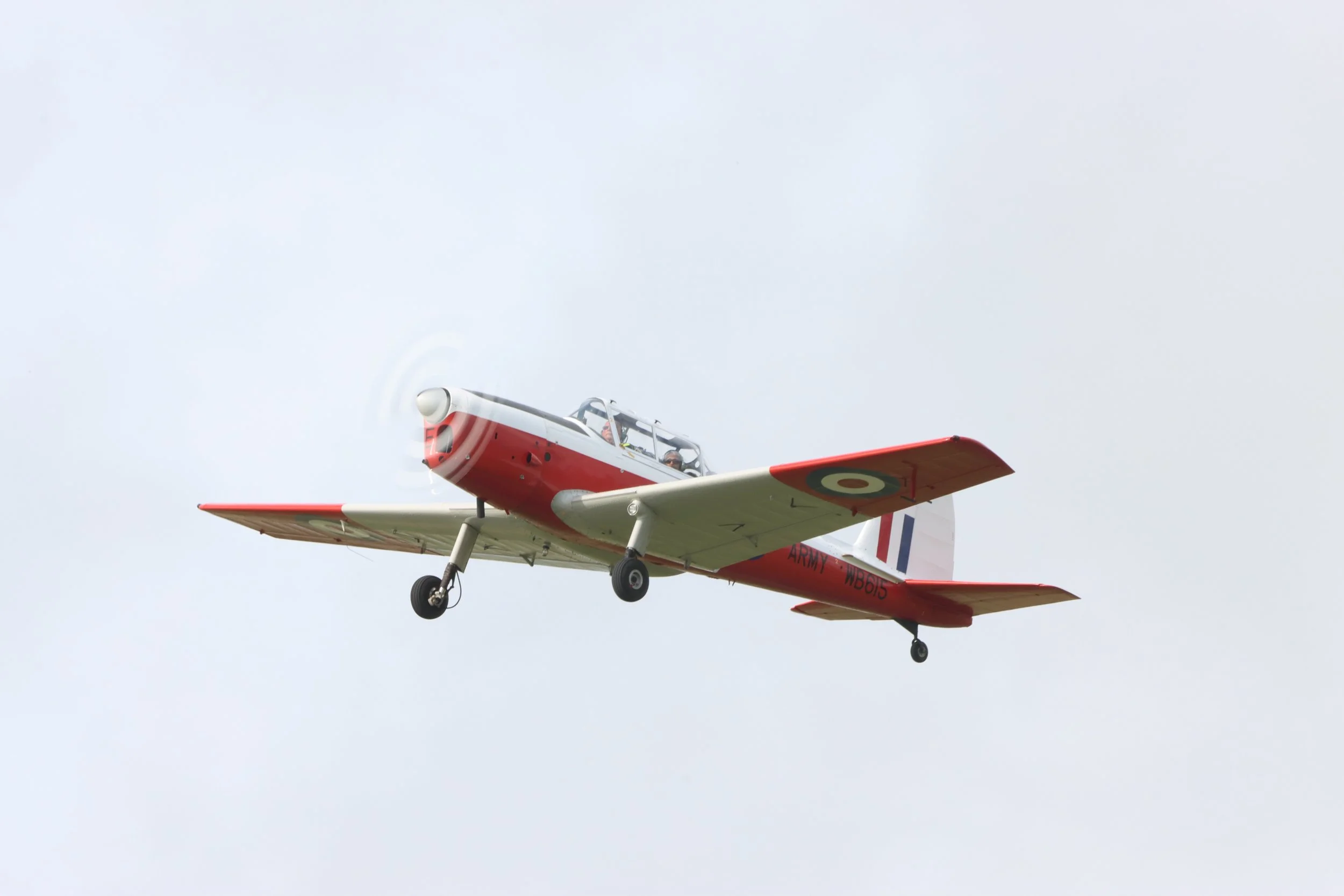 A vintage Red Arrow aircraft flying in overcast sky.
