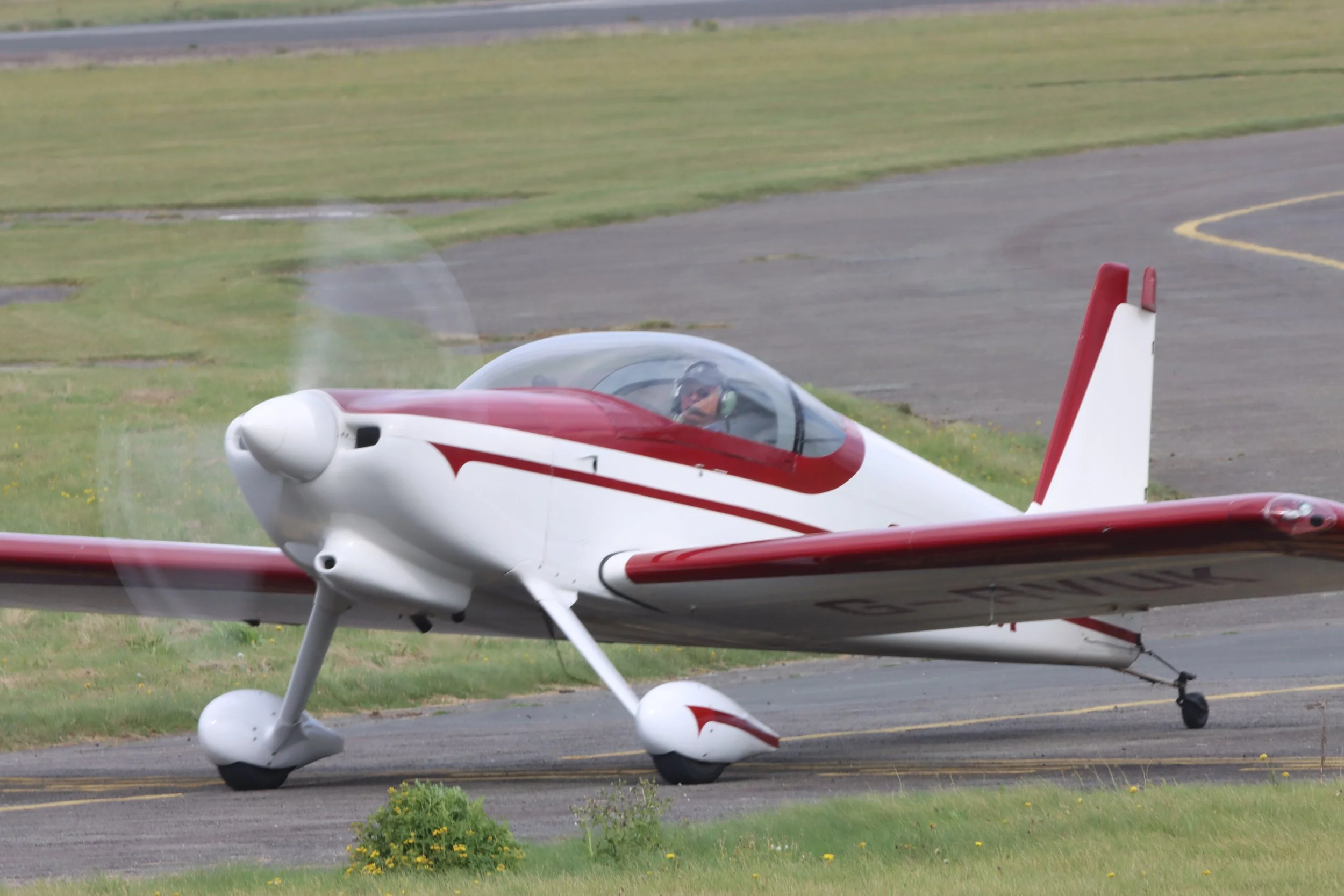 Small white and red propeller airplane on the ground at an airport runway.