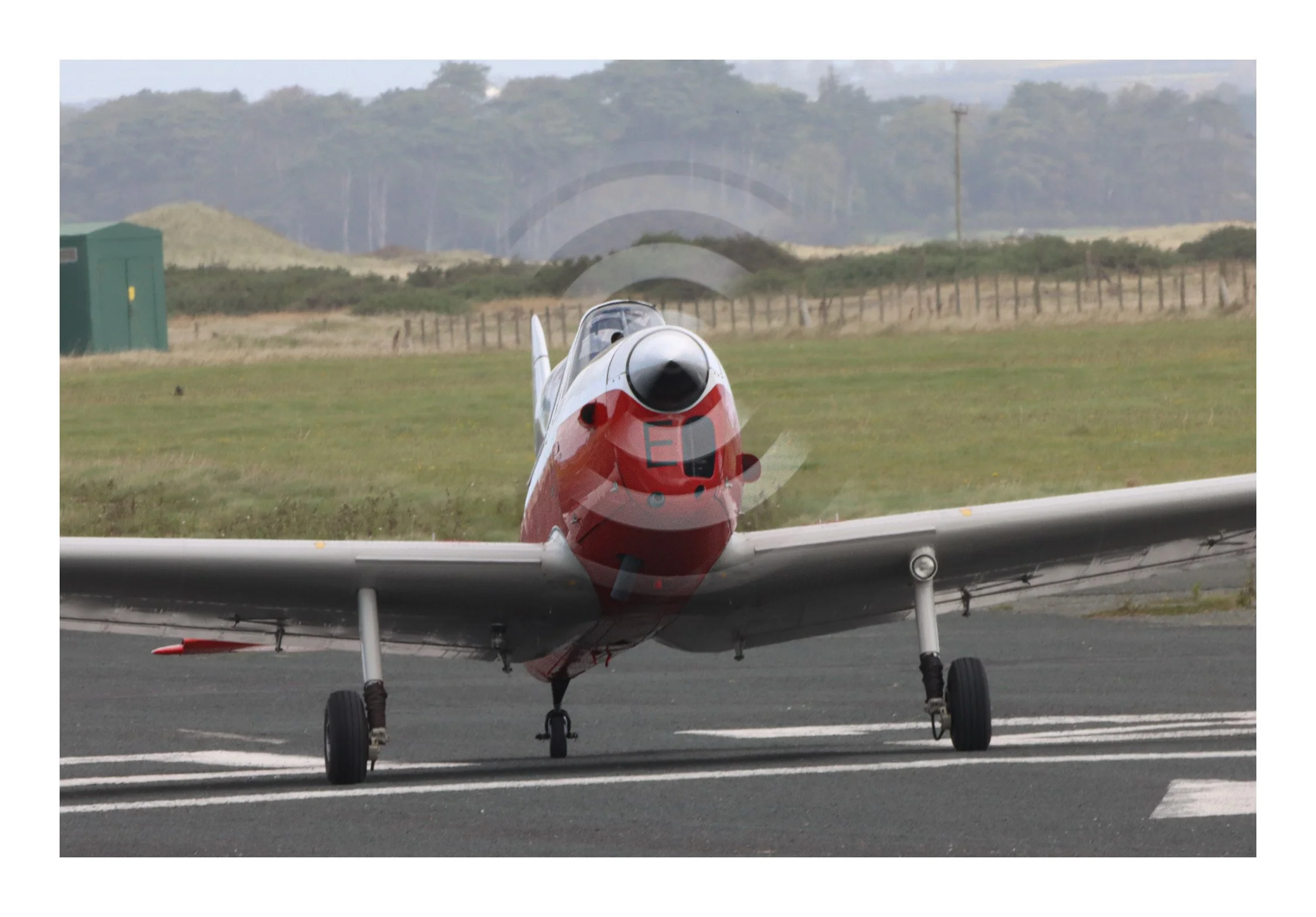 A fighter jet on a runway preparing for takeoff with a scenic landscape in the background.