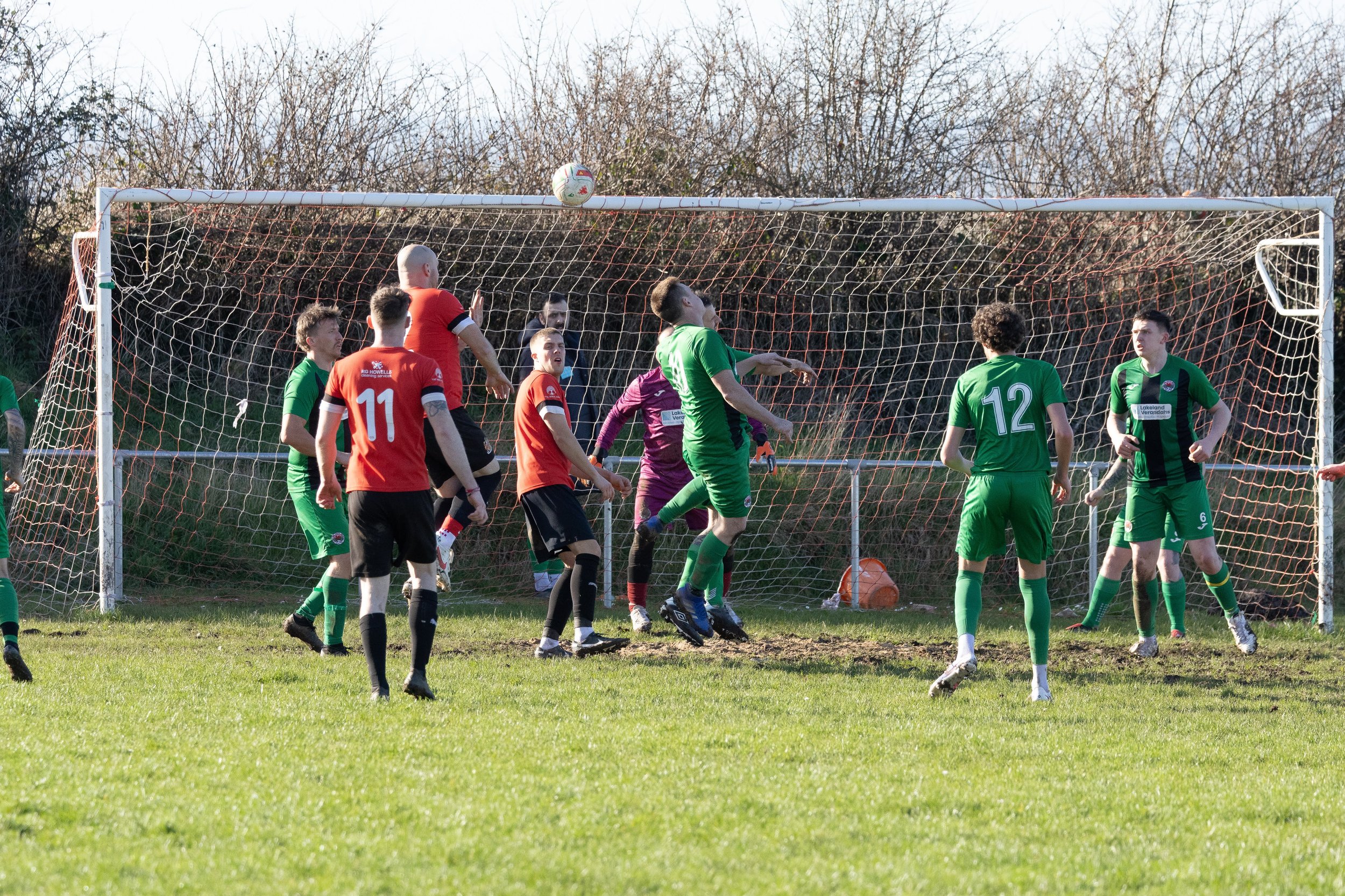 Soccer players on the field, with some jumping and attempting to head the ball near the goal during a game.