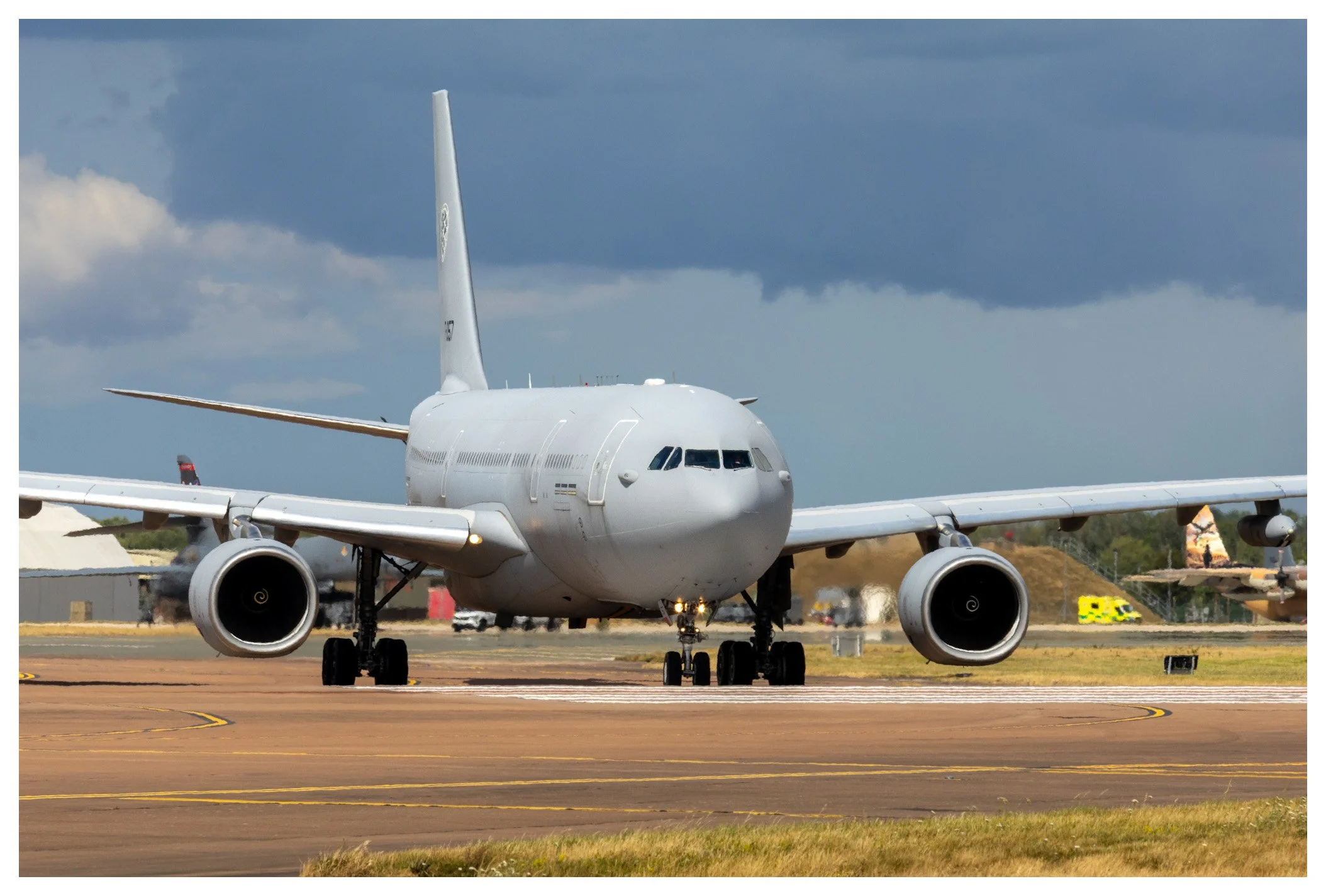 A large white airplane on the runway during daytime with dark clouds in the sky.
